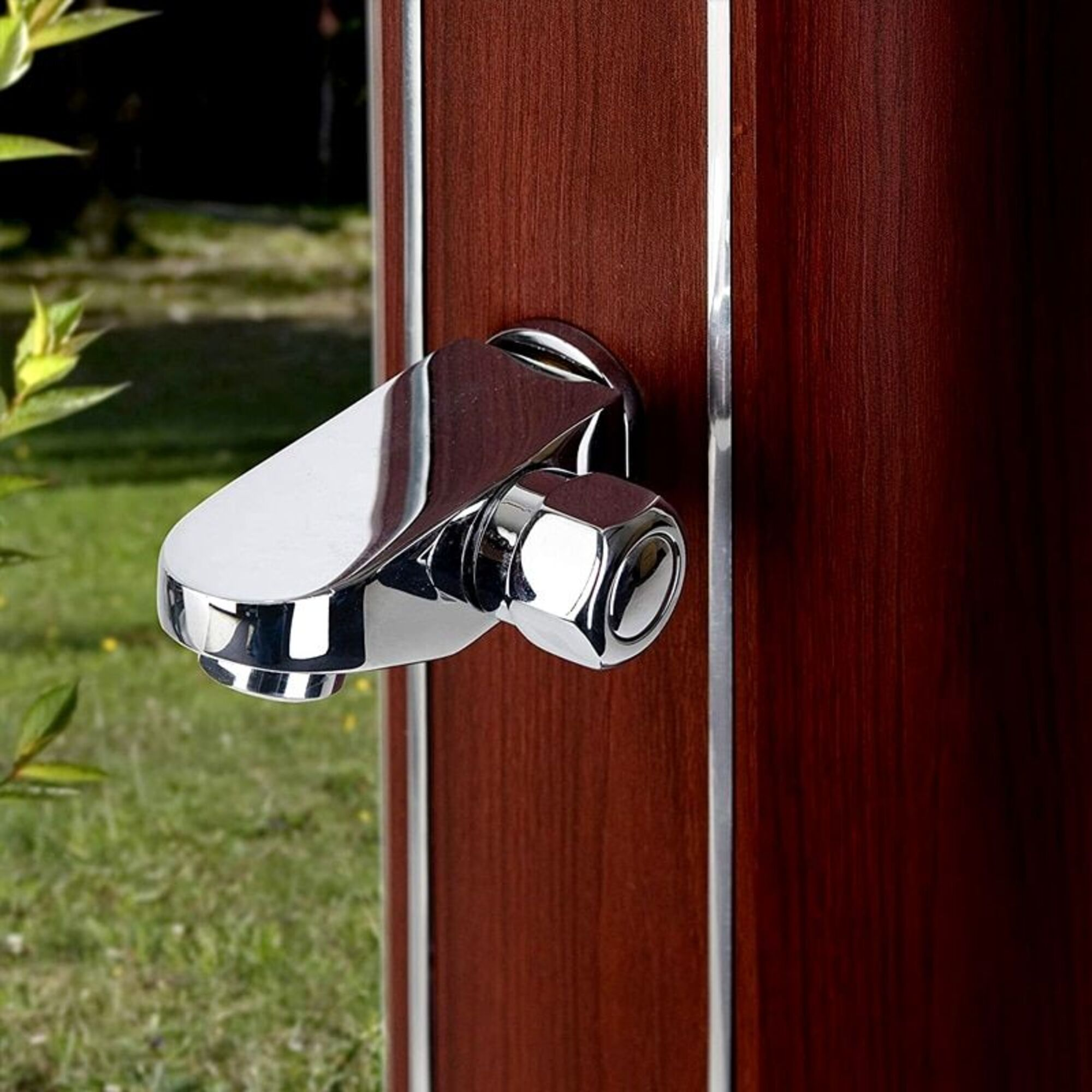 Un grifo cromado con mango hexagonal está montado en un panel de madera oscura con borde plateado.