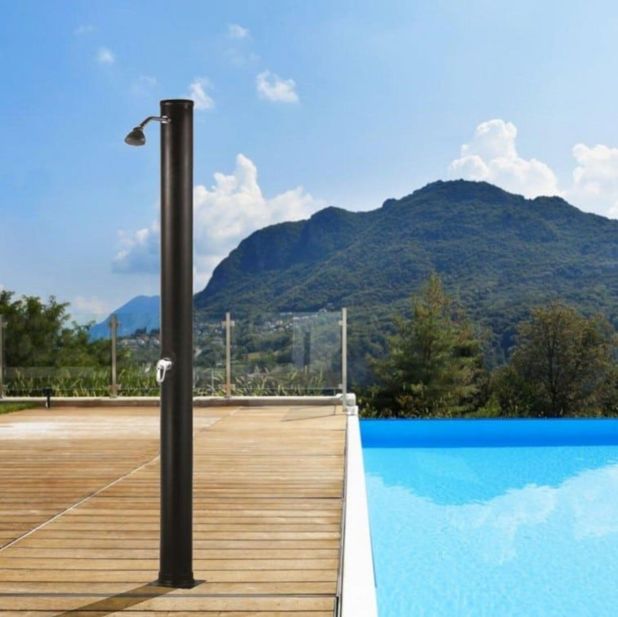 Ducha exterior junto a piscina azul brillante, tarima de madera, montañas y cielo.