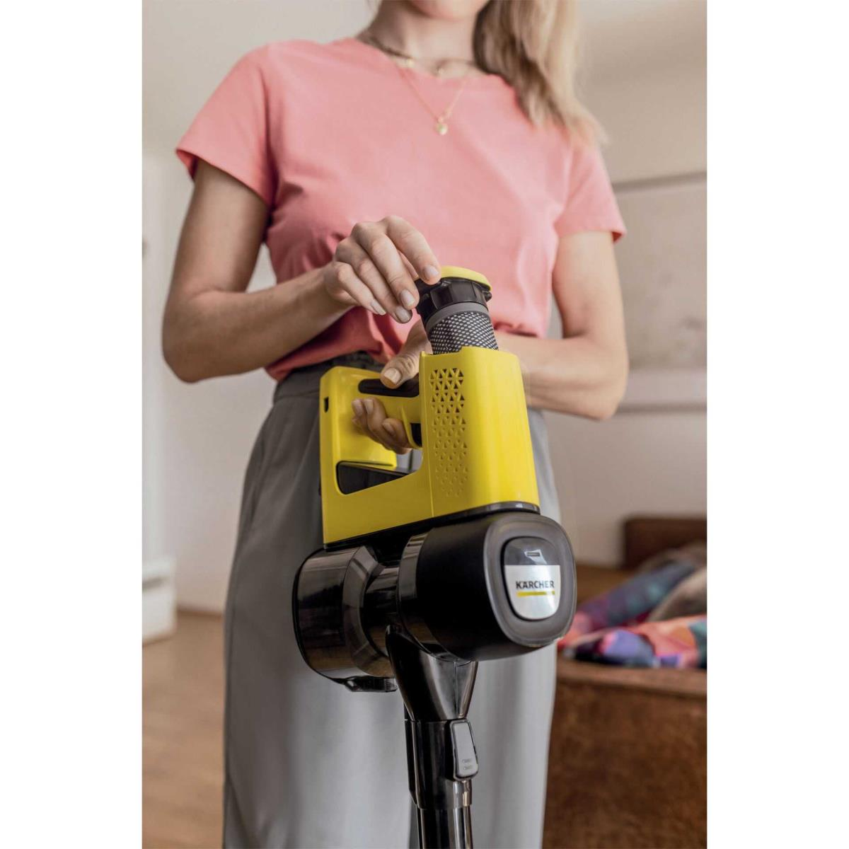 Una donna tiene un aspirapolvere senza fili Karcher giallo, cambiandone il filtro.