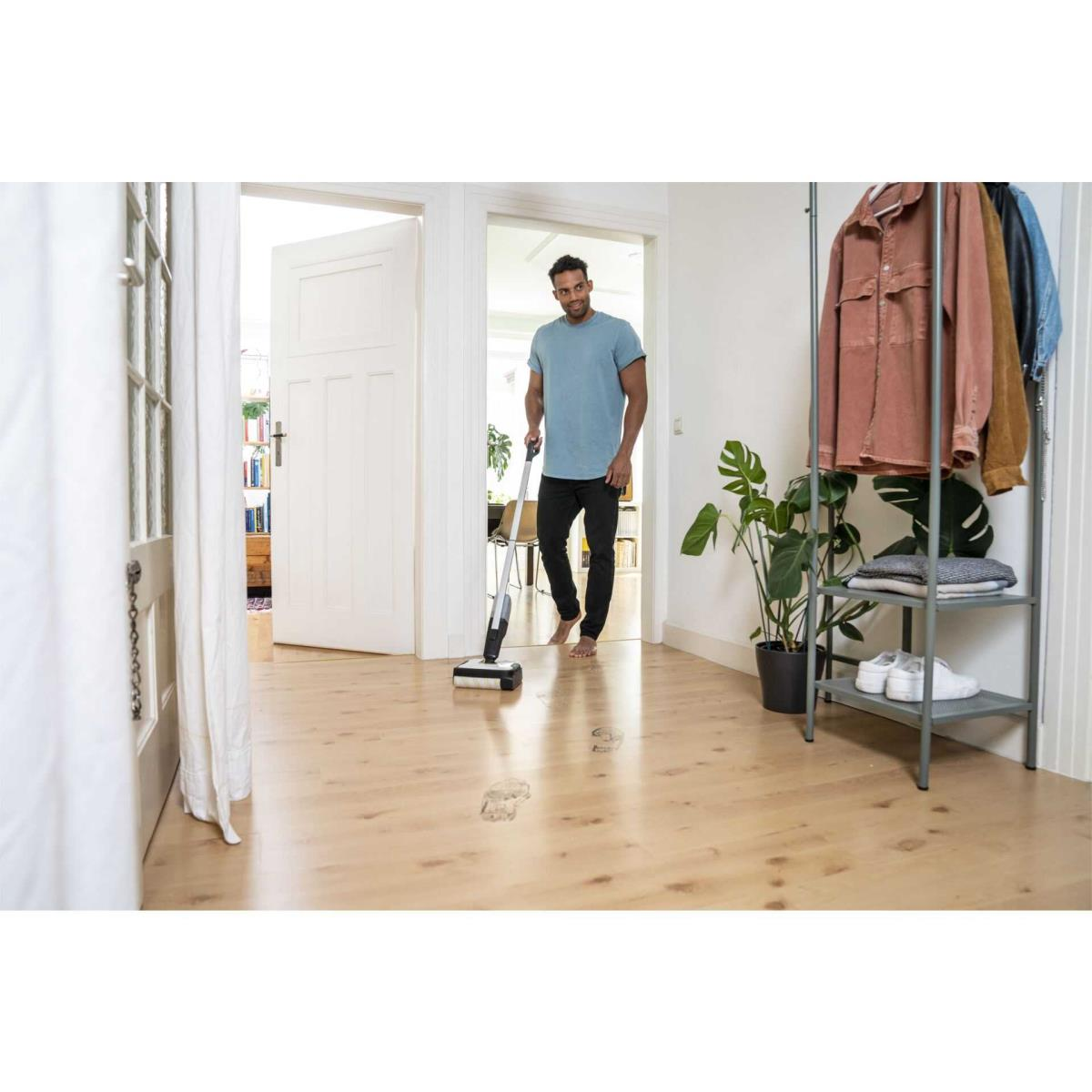 Un homme passe la serpillière sur un parquet avec une serpillière sans fil.