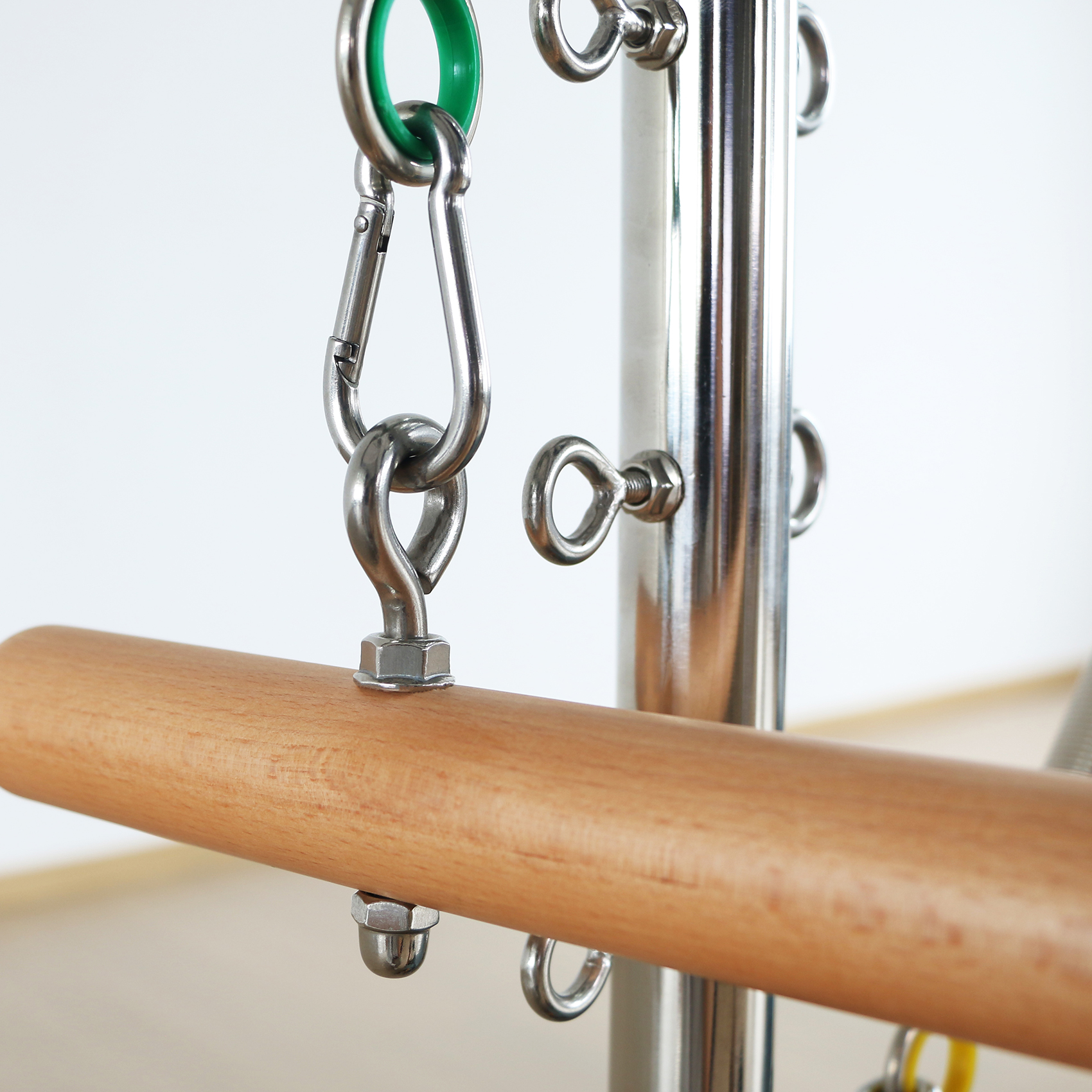 Ein Holzgriff mit Metallbefestigungen an einem silbernen Pilates-Gerät.