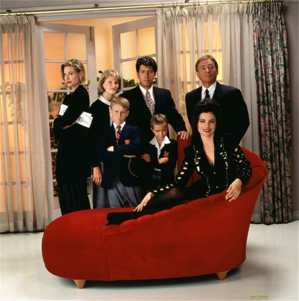 Una donna elegante è sdraiata su una chaise longue rossa con una famiglia dietro.