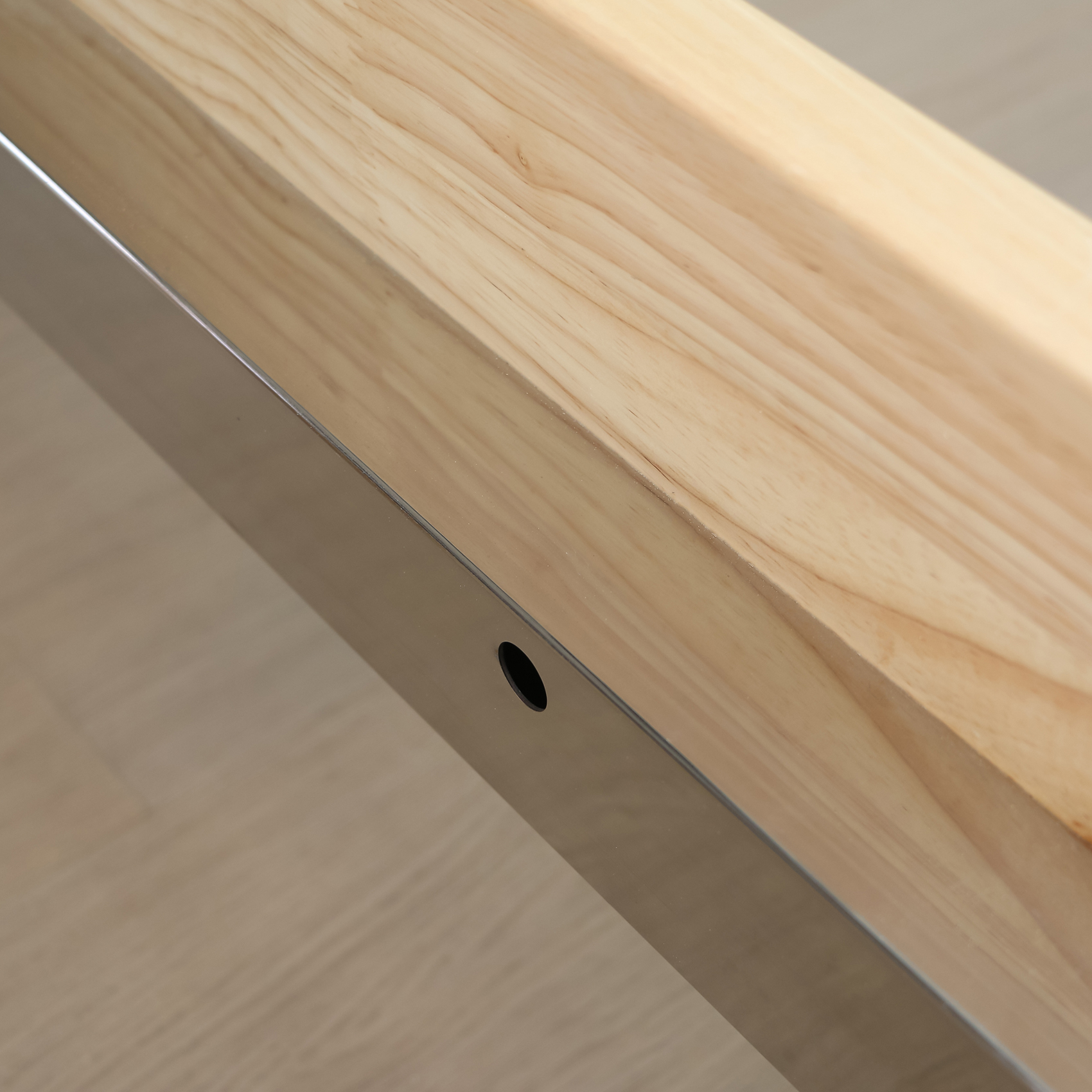 Holzbalken mit polierter Metallleiste und einem Loch.