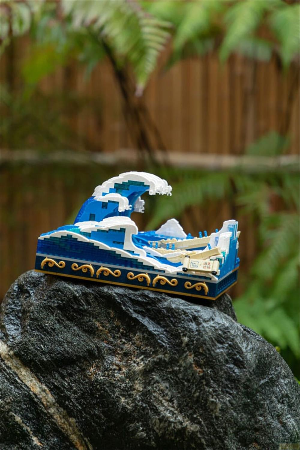 Un modèle Lego d'une vague avec un bateau sur un rocher.