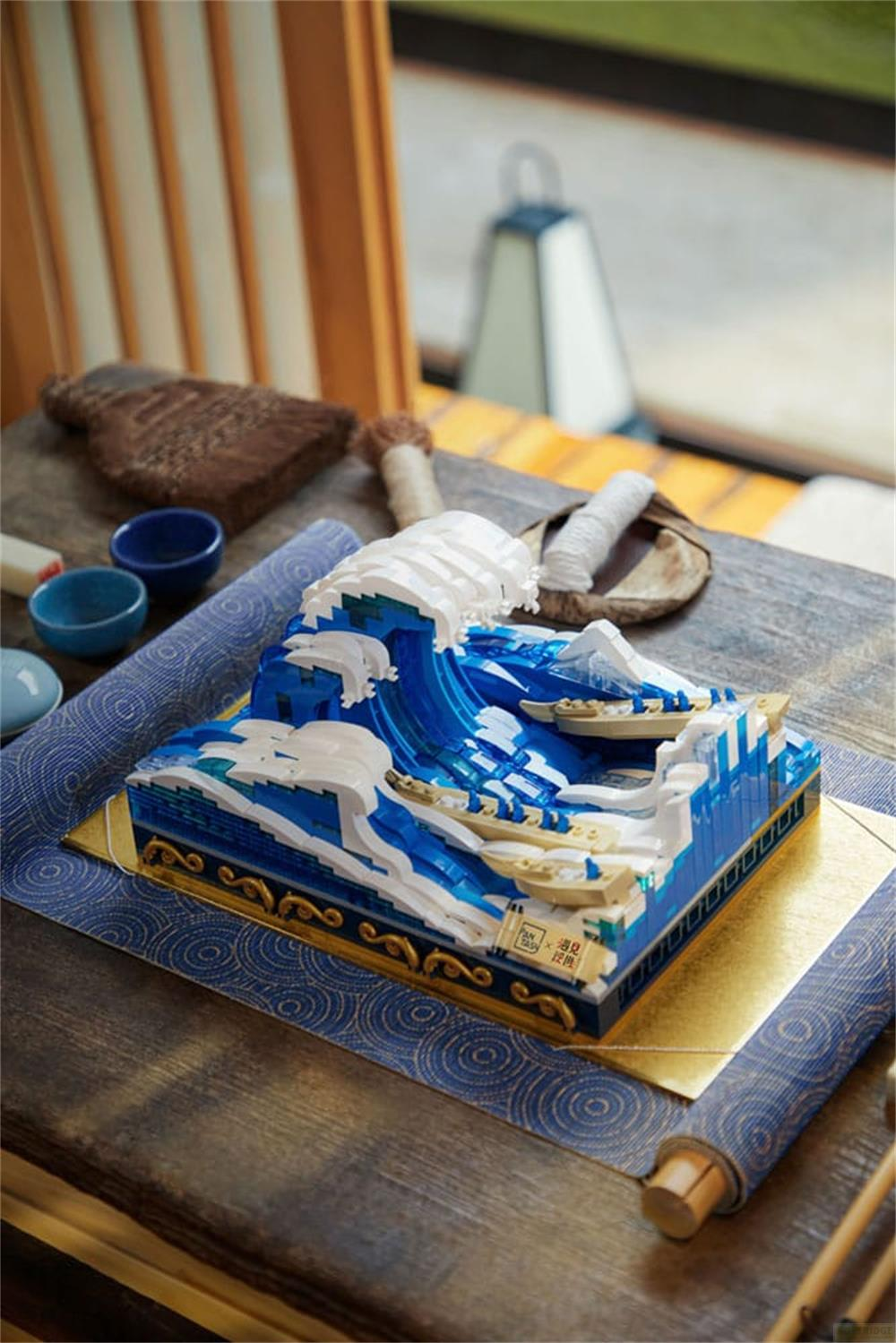 Modèle Lego détaillé d'une vague avec des bateaux, sur une table avec des bols.