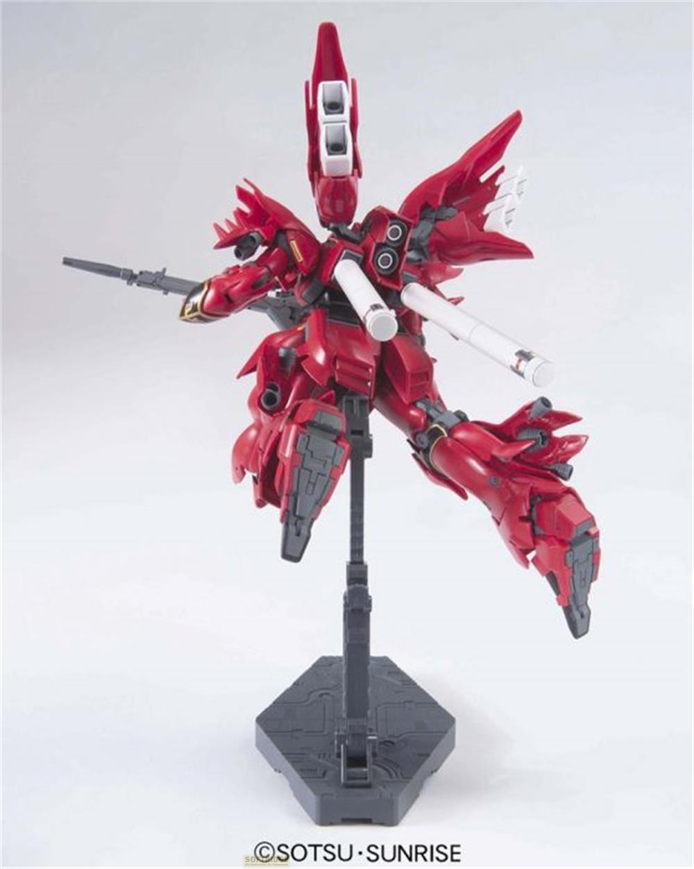 Ein roter Gundam-Roboter mit Waffen steht auf einem dunklen Ständer.