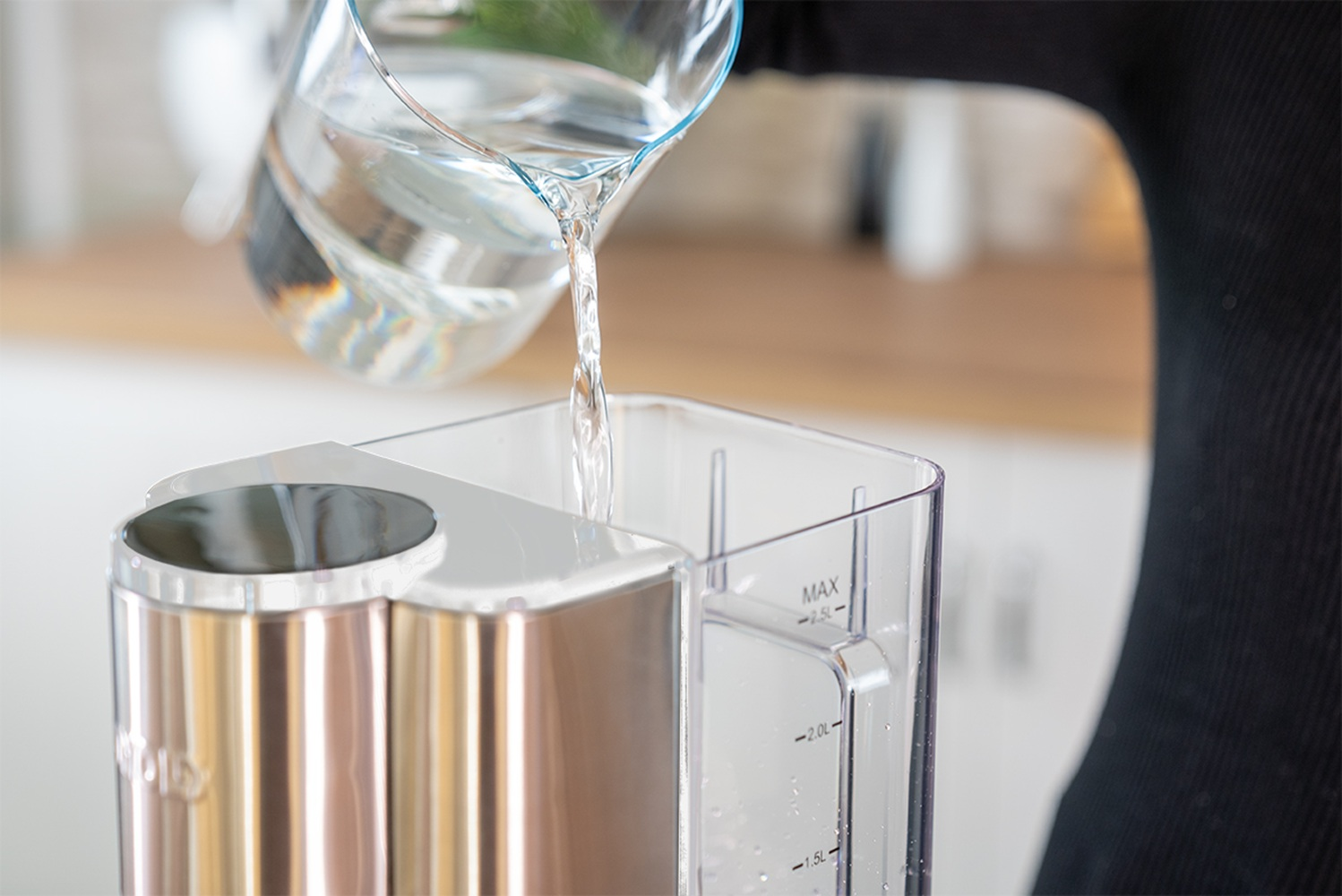 Wasser wird aus einem Glasbehälter in ein Gerät gegossen.