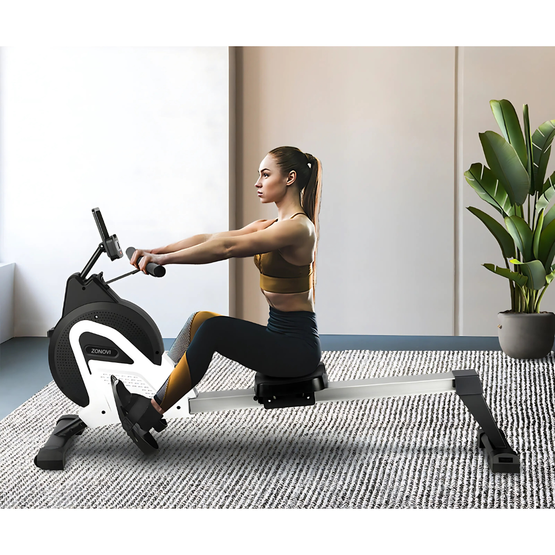 A woman exercises on a rowing machine in a bright room with a rug and a plant.