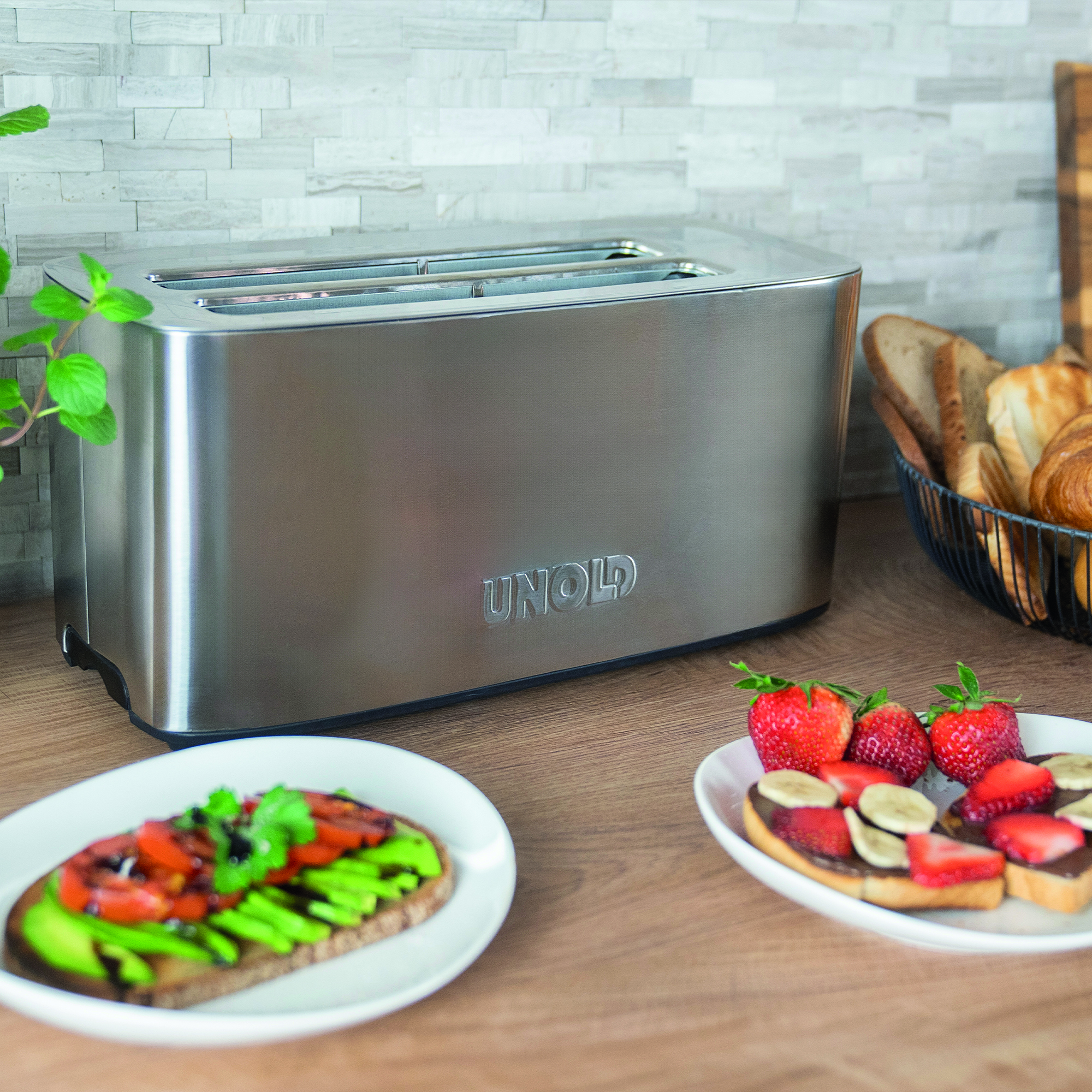 Ein silberner Toaster steht auf einer Holzoberfläche mit Brot und Croissants.