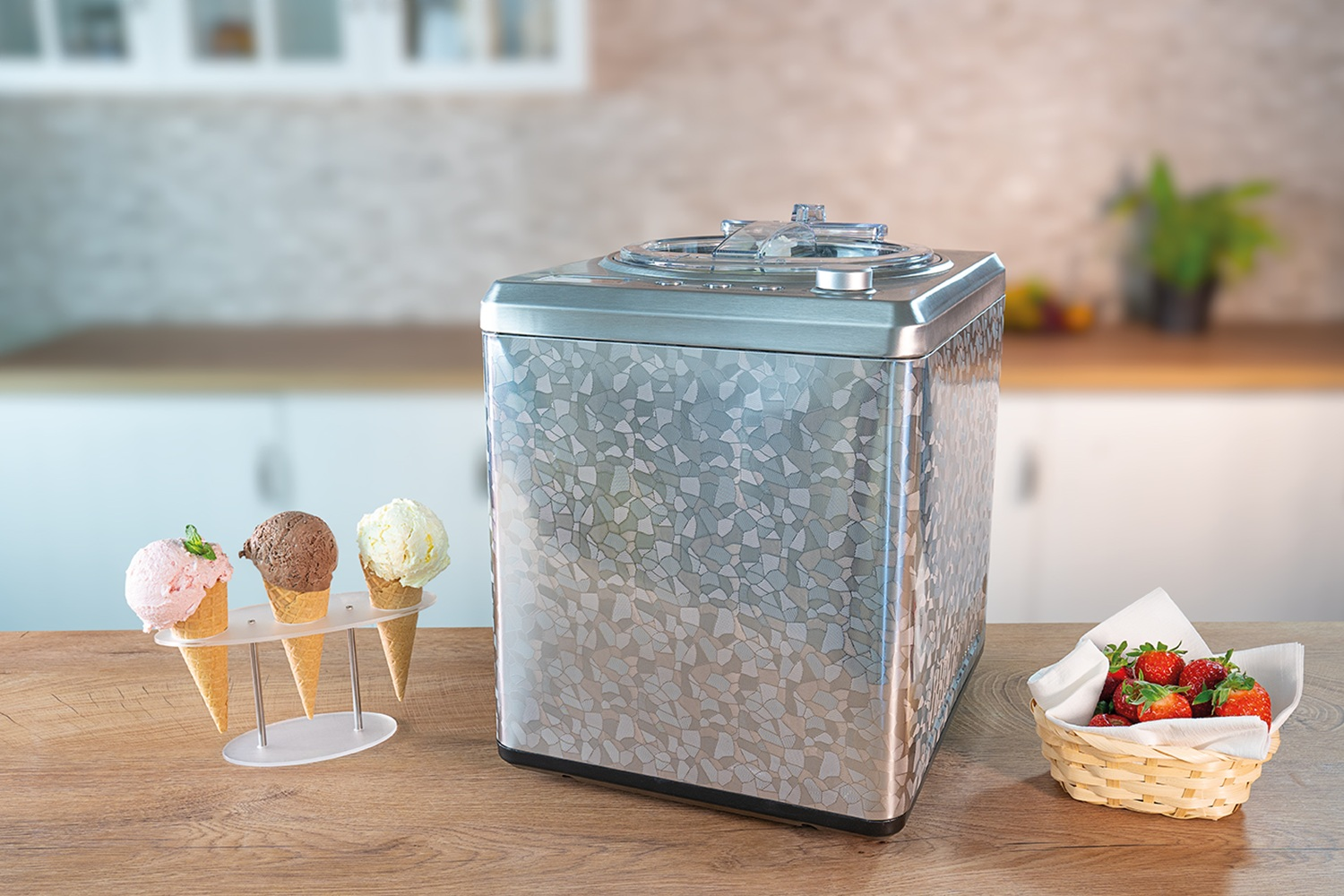 Eismaschine mit Mosaikmuster, dazu drei Eiswaffeln und eine Schale Erdbeeren.
