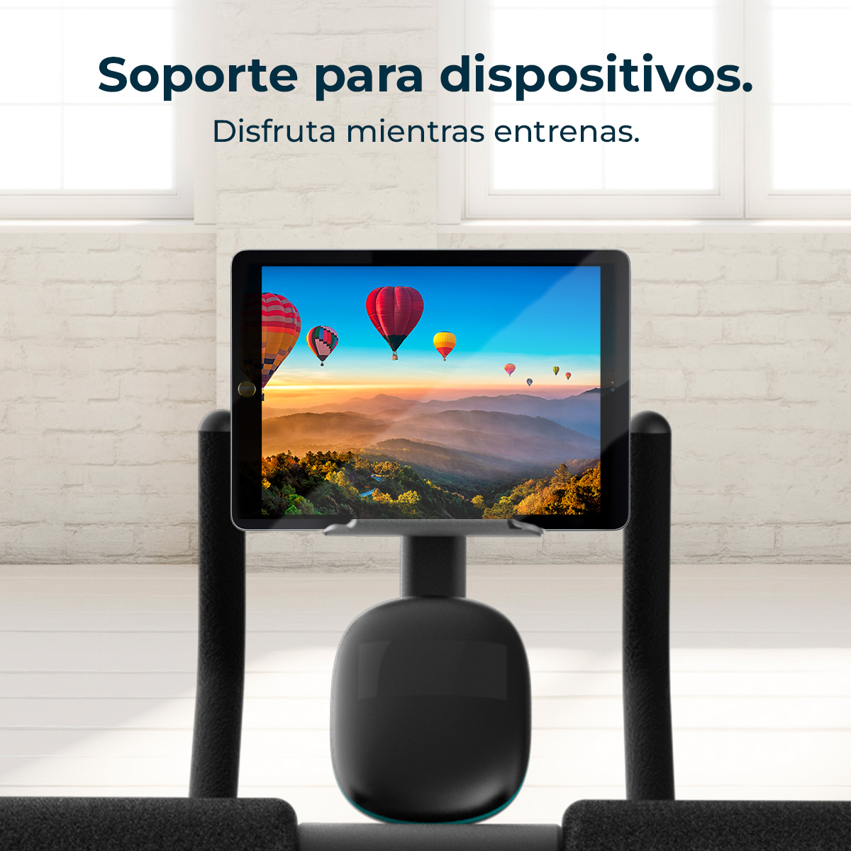 Tablet wyświetlający balony na gorące powietrze nad górskim krajobrazem na rowerze stacjonarnym.