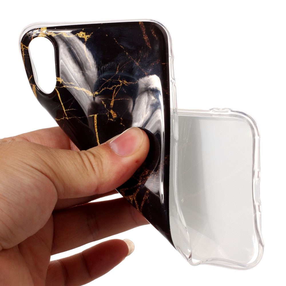 Una mano tiene una cover per telefono in marmo nero con venature dorate.