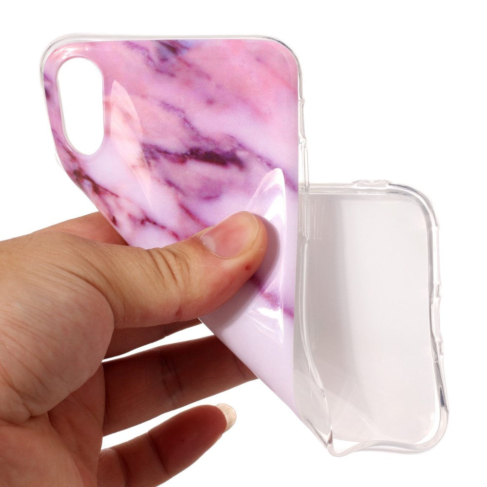 Una mano tiene una cover trasparente per telefono con motivo marmo rosa.