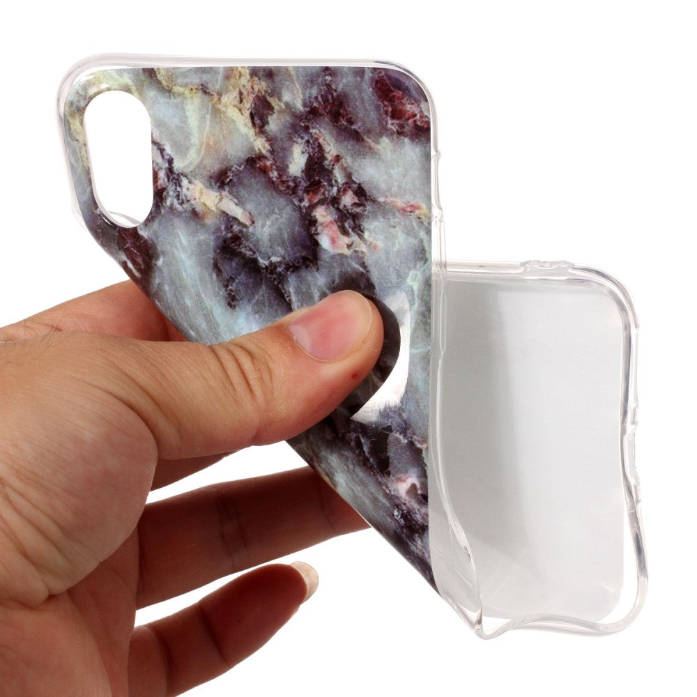 Una mano tiene una cover trasparente per telefono con motivo marmoreo.