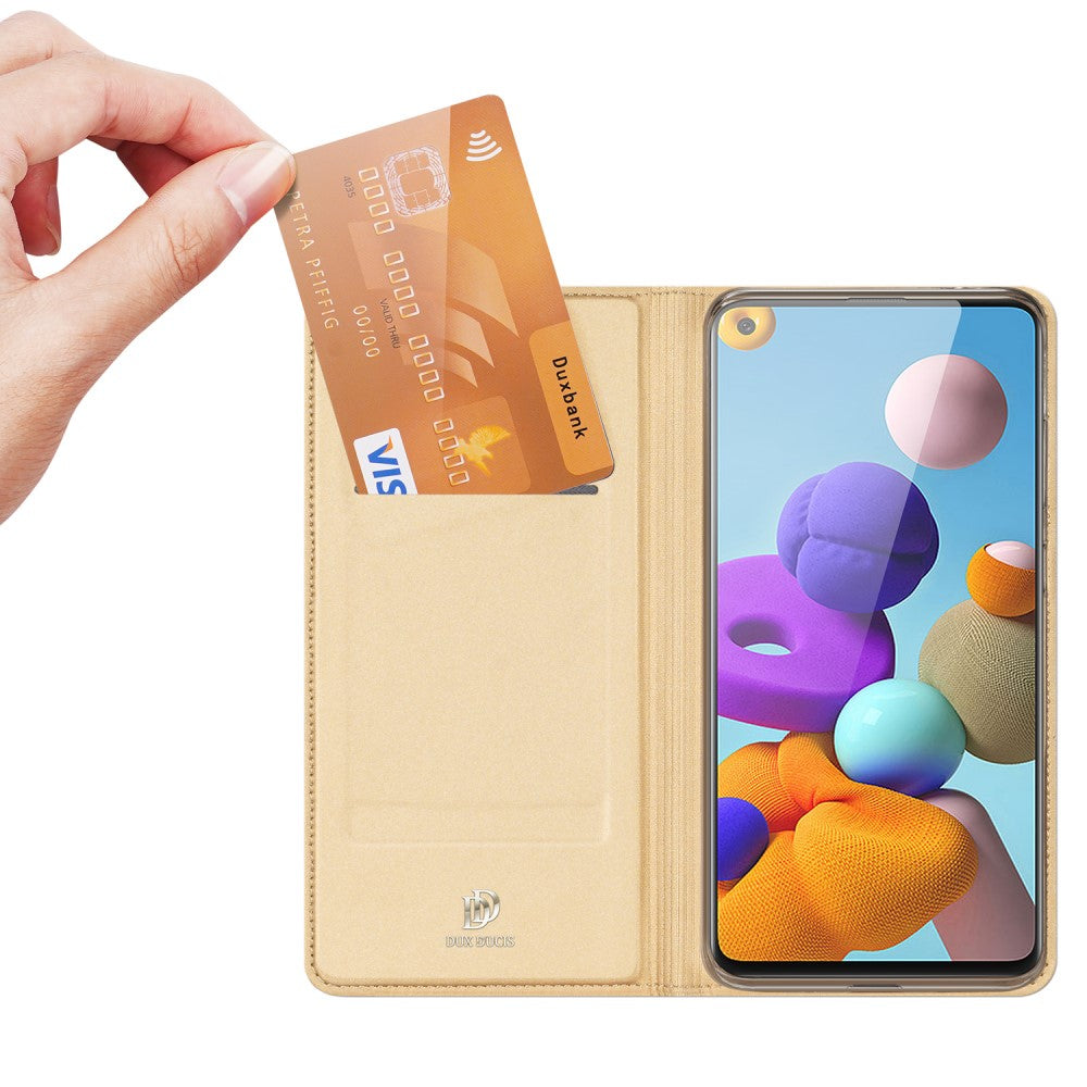 Una mano inserisce una carta di credito dorata in una custodia per telefono beige.