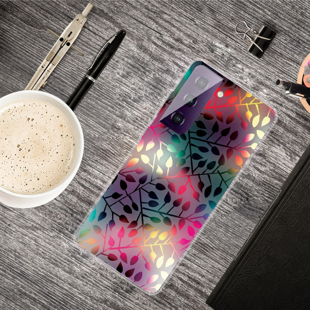Uno smartphone con grafica a foglie colorate poggia su una scrivania di legno accanto a caffè e cancelleria.