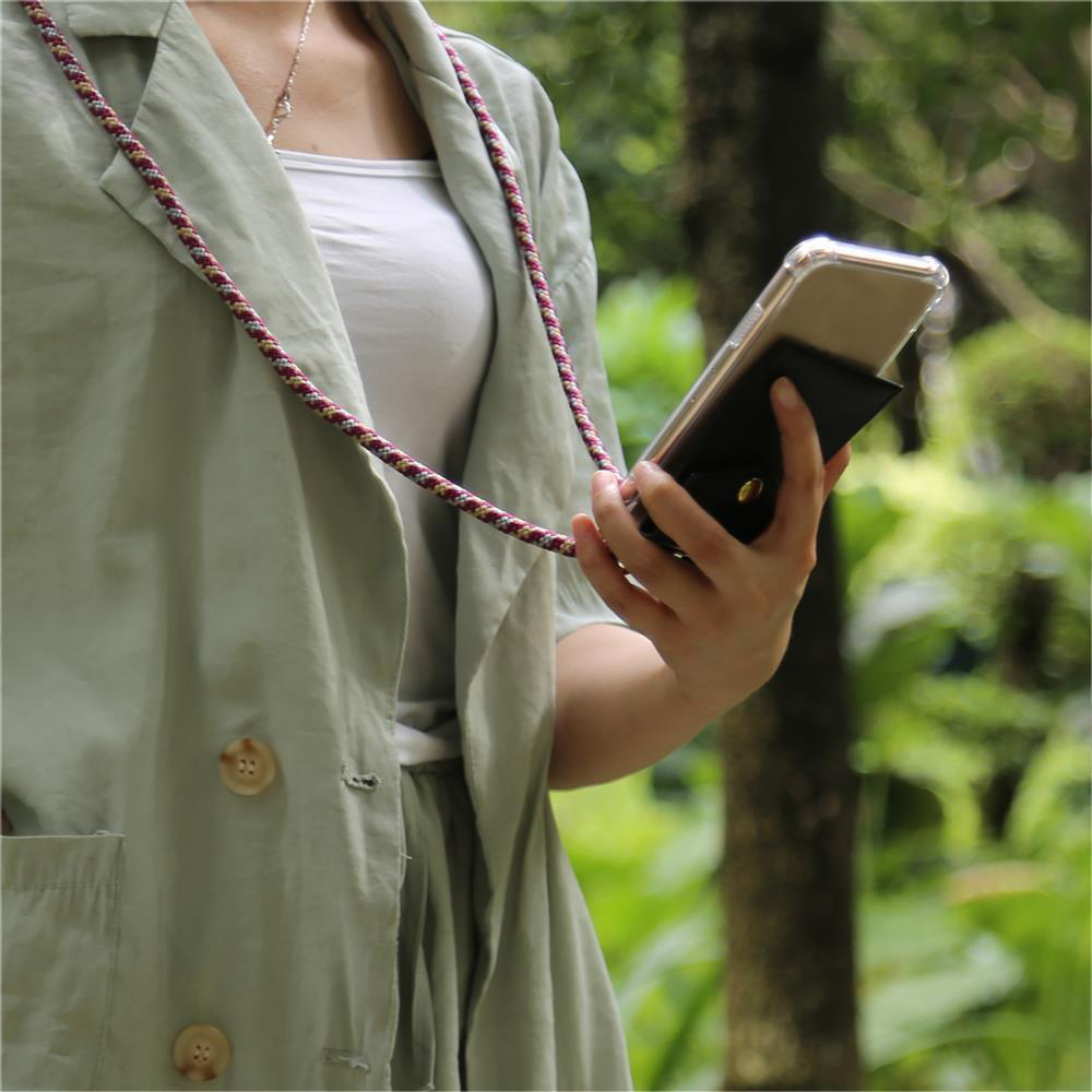 Una persona in outfit verde chiaro tiene uno smartphone con portafoglio.