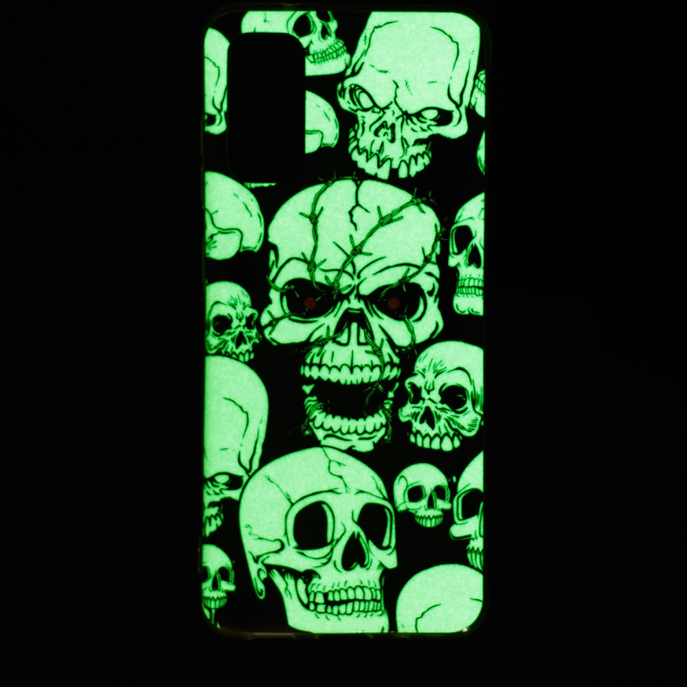 Una cover nera per telefono con teschi verdi luminosi e occhi rossi.