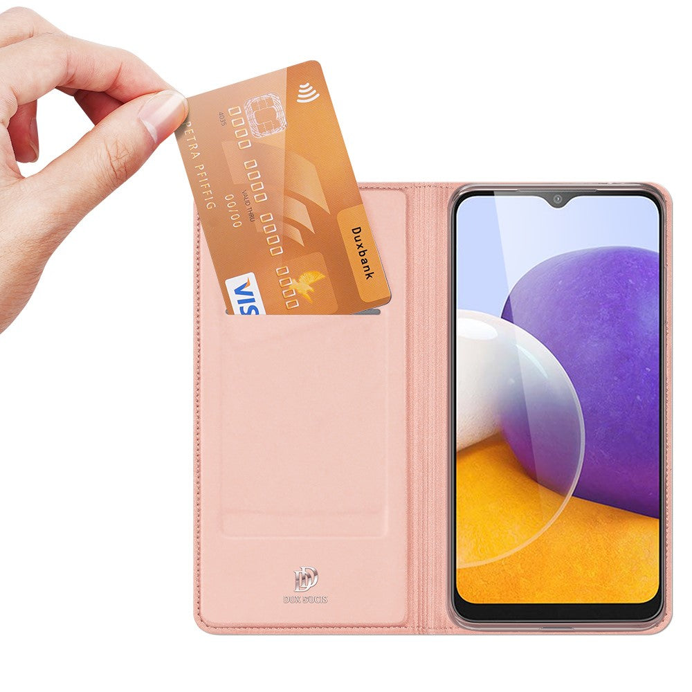 Una mano inserisce una carta Visa dorata in una custodia rosa per telefono accanto a uno smartphone.