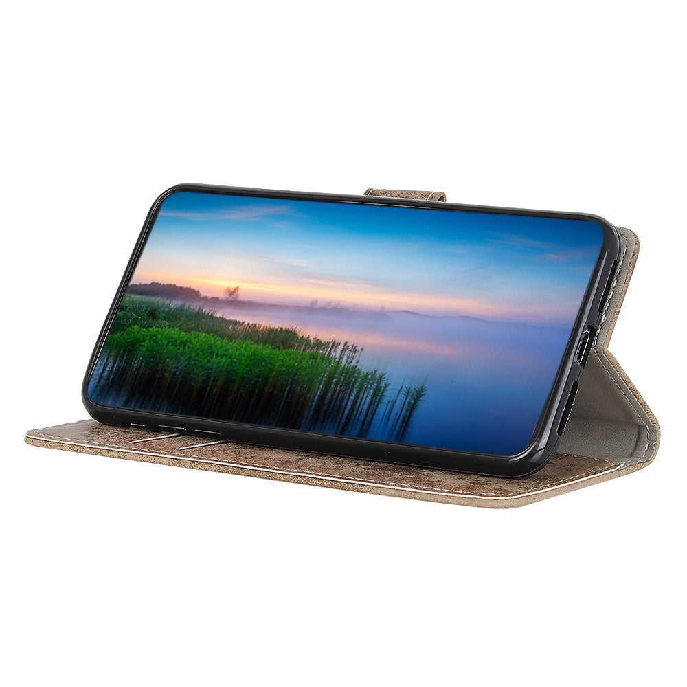 Un telefono cellulare in custodia marrone mostra un paesaggio con canne e tramonto.