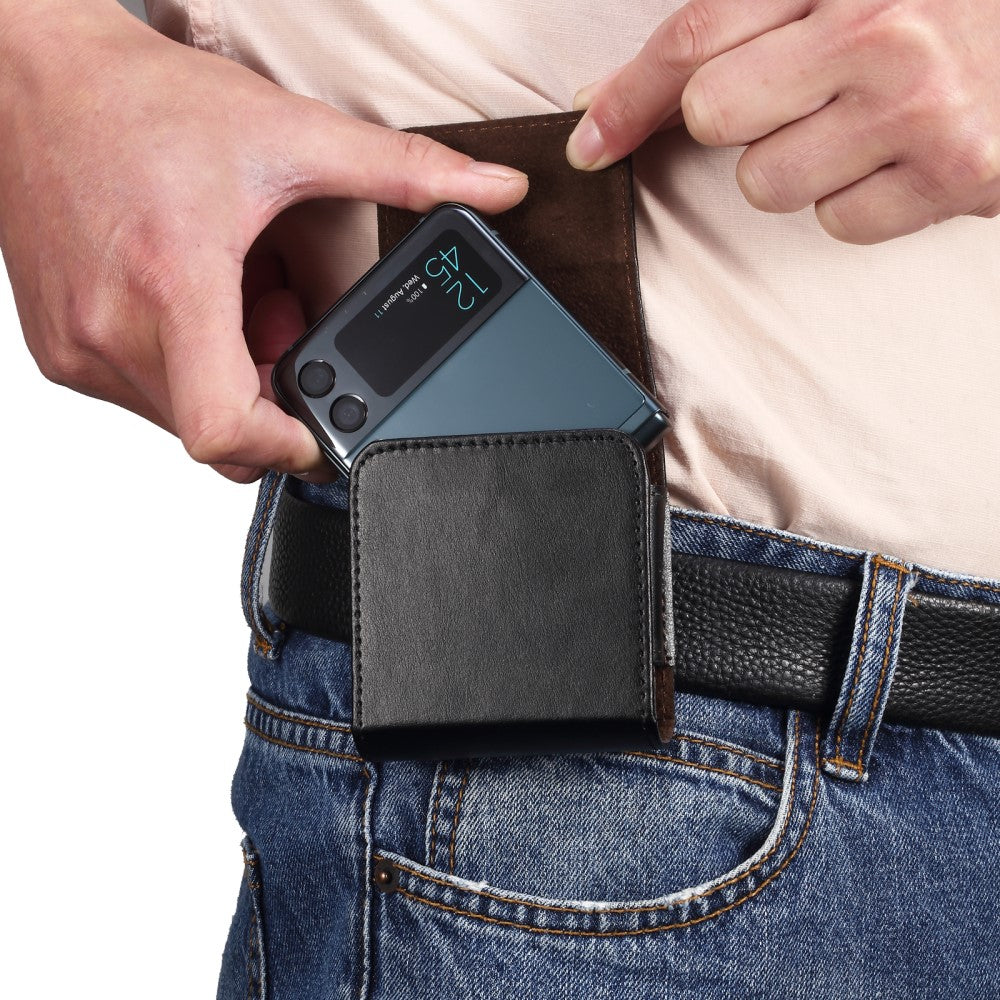 Una persona inserisce un telefono flip blu in una custodia in pelle nera alla cintura.