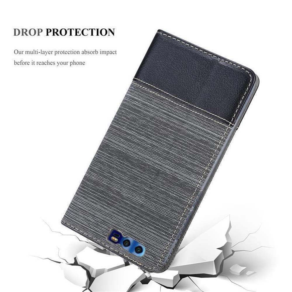 Custodia per telefono grigia con copertina in pelle nera che cade su blocchi bianchi rotti su sfondo bianco.