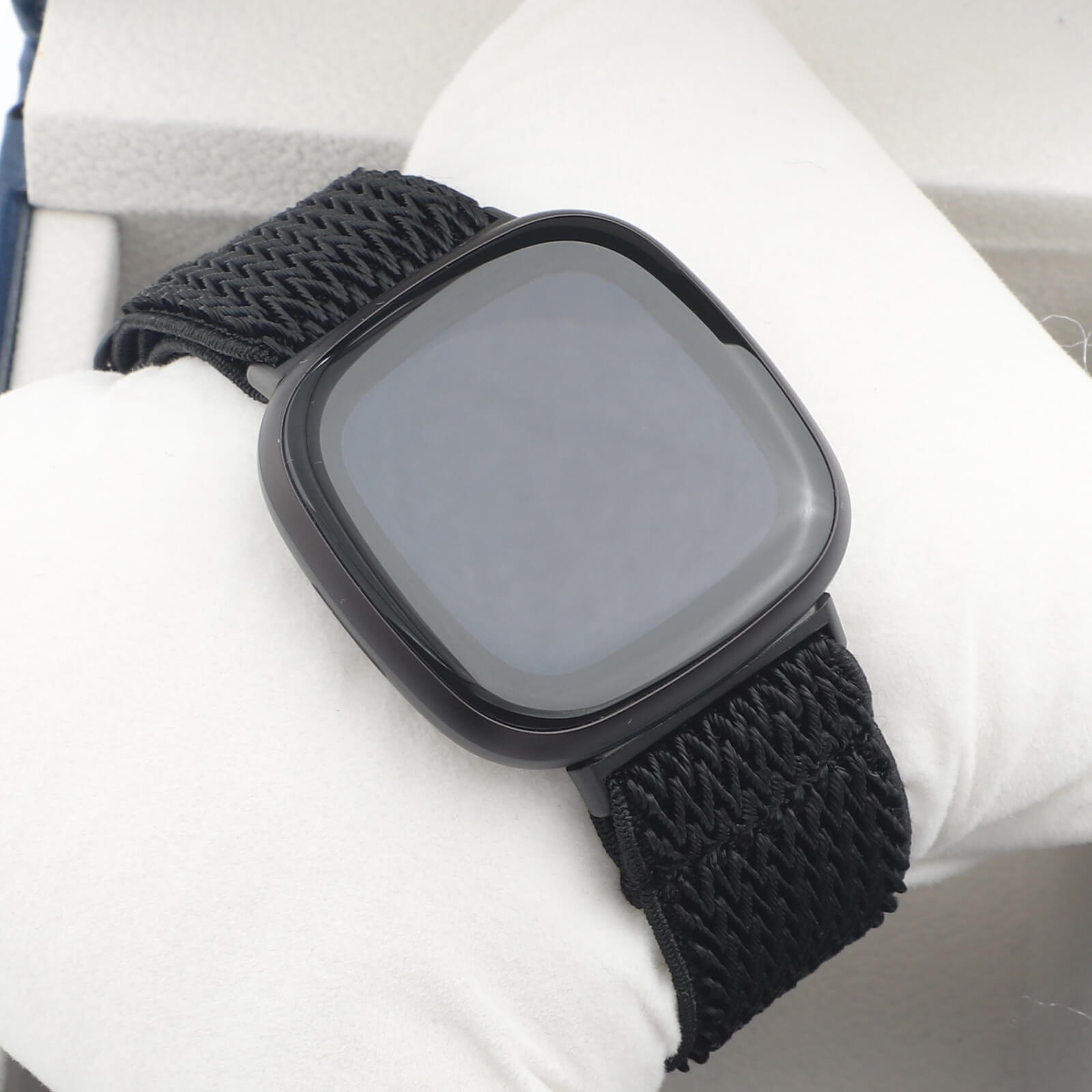 Un bracelet de montre connectée en tissu noir avec un écran carré.