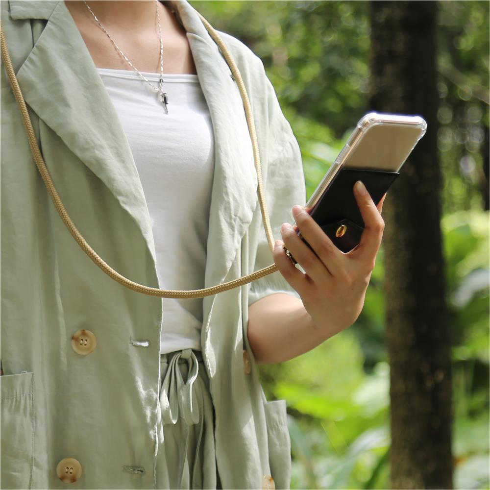 Una persona in giacca verde chiaro tiene uno smartphone con supporto nero.
