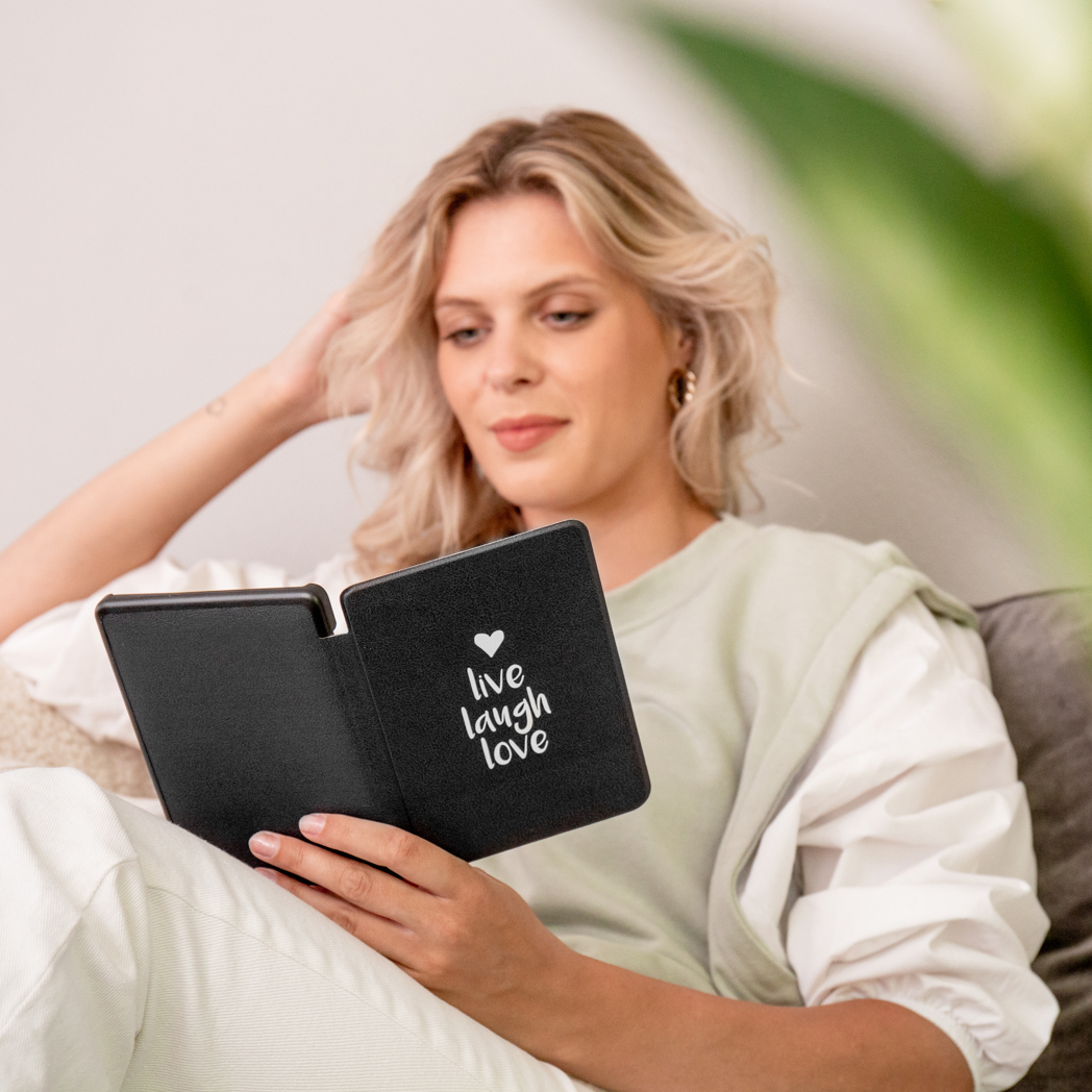 Une femme lit un livre noir avec « live laugh love » écrit dessus.