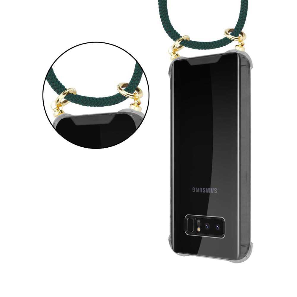 Telefono Samsung nero in custodia trasparente con laccetto verde e anelli dorati.