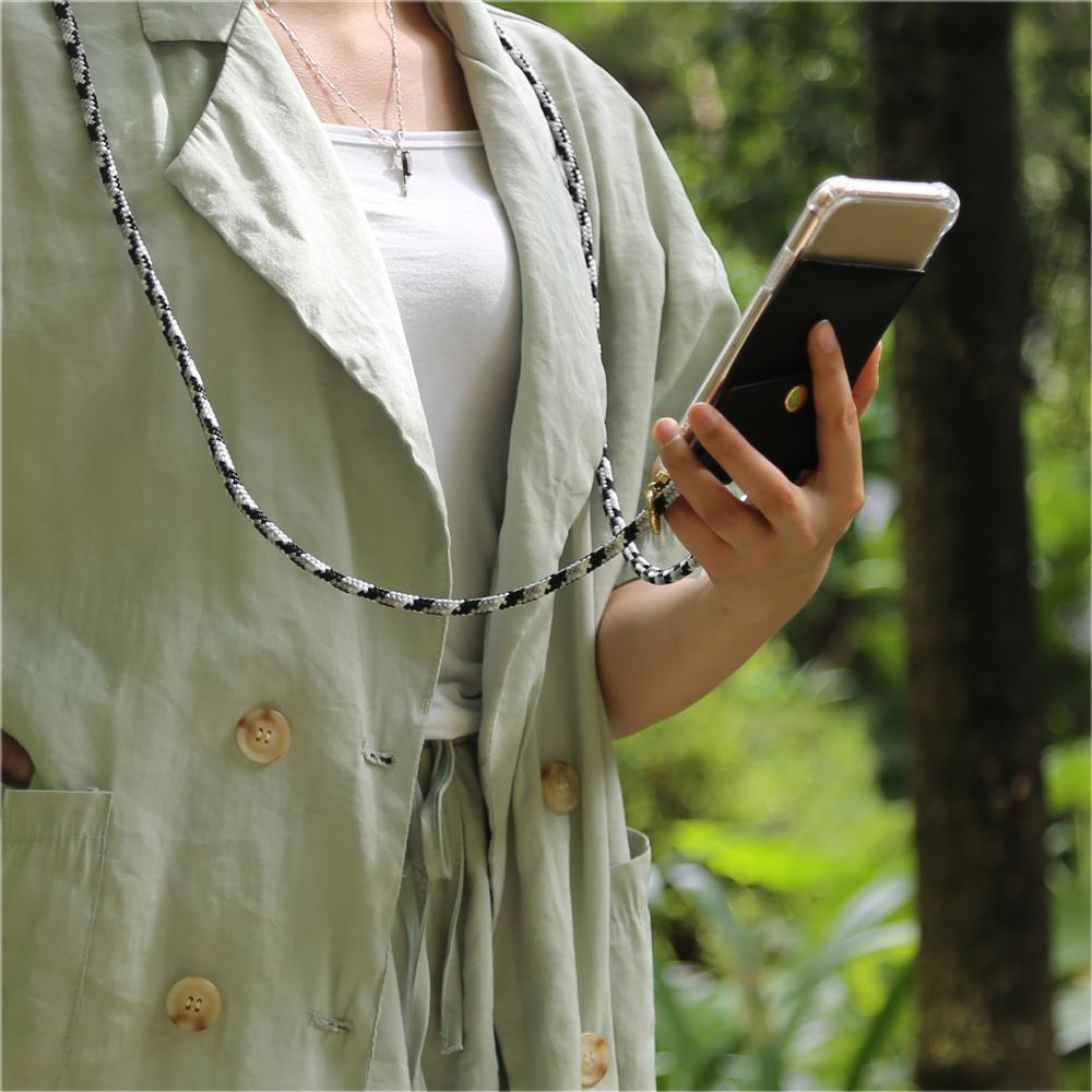 Una persona in giacca verde chiaro tiene uno smartphone con custodia nera.
