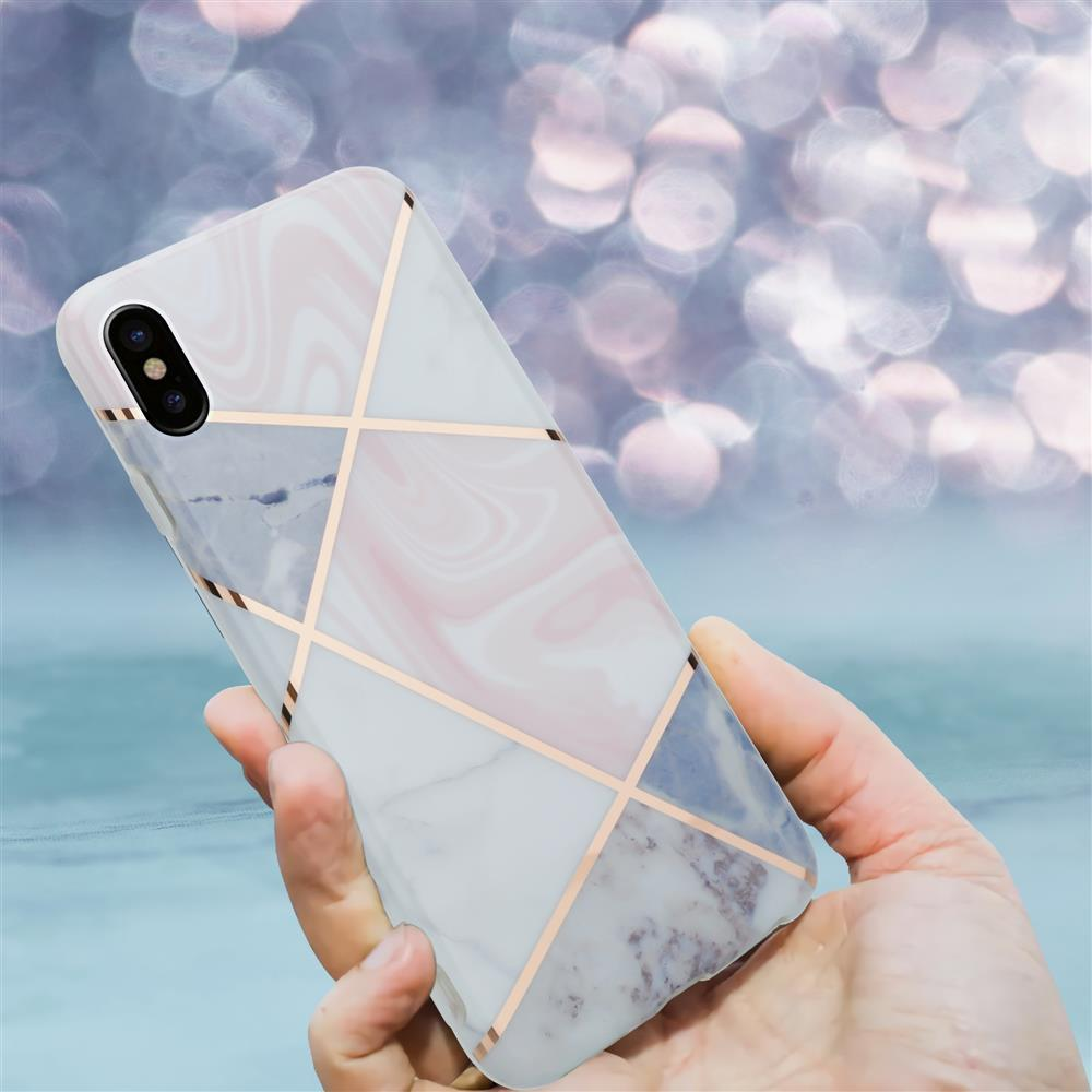 Una mano tiene uno smartphone con design in marmo e linee dorate.