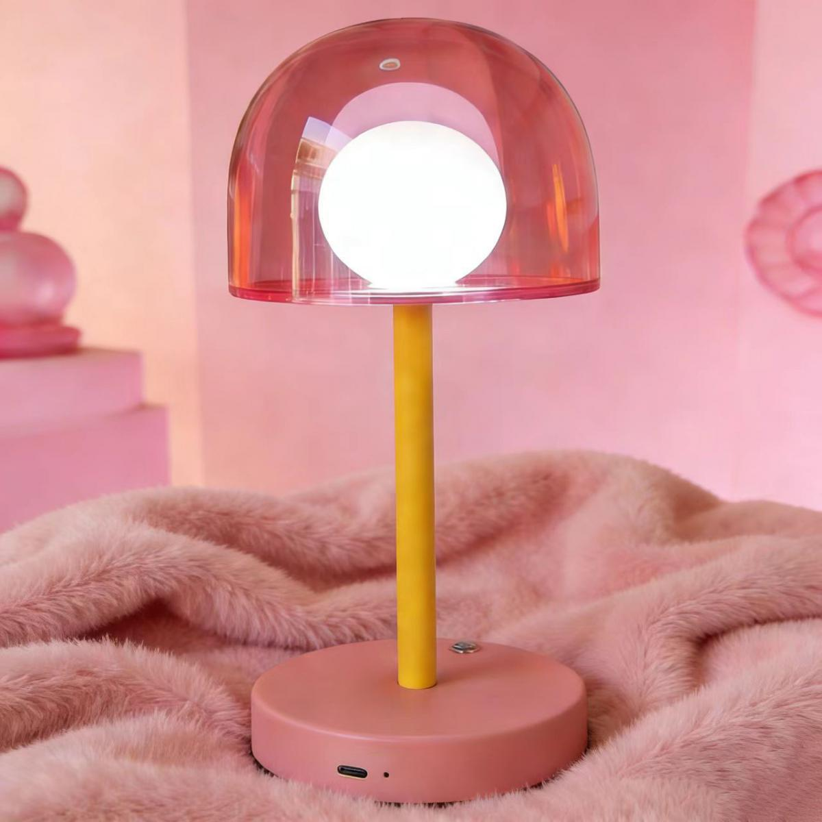 Eine pinke Lampe mit gelbem Stiel und Glühbirne auf einem rosa Teppich.
