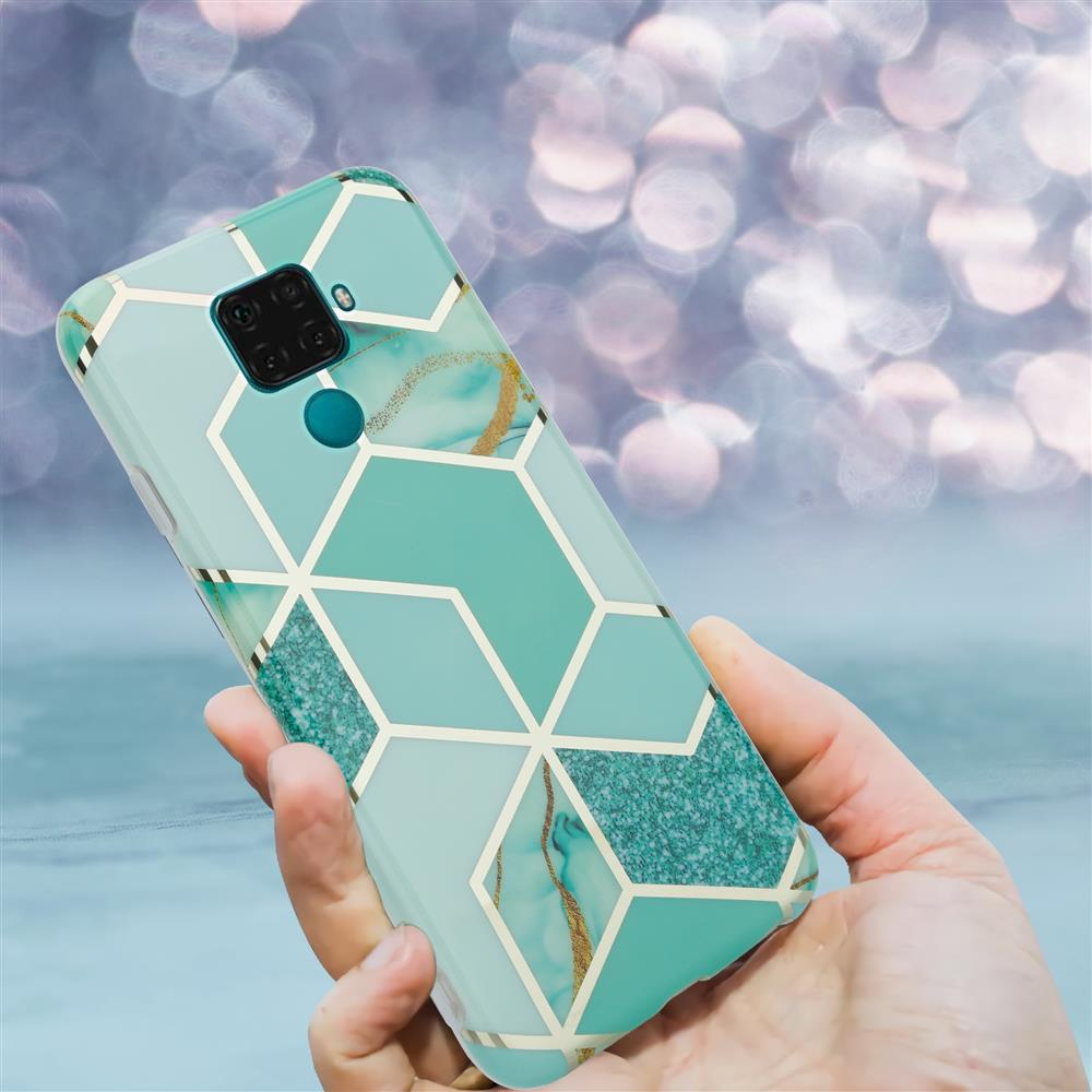 Una mano tiene un telefono con motivo geometrico verde acqua. Sfondo sfocato.