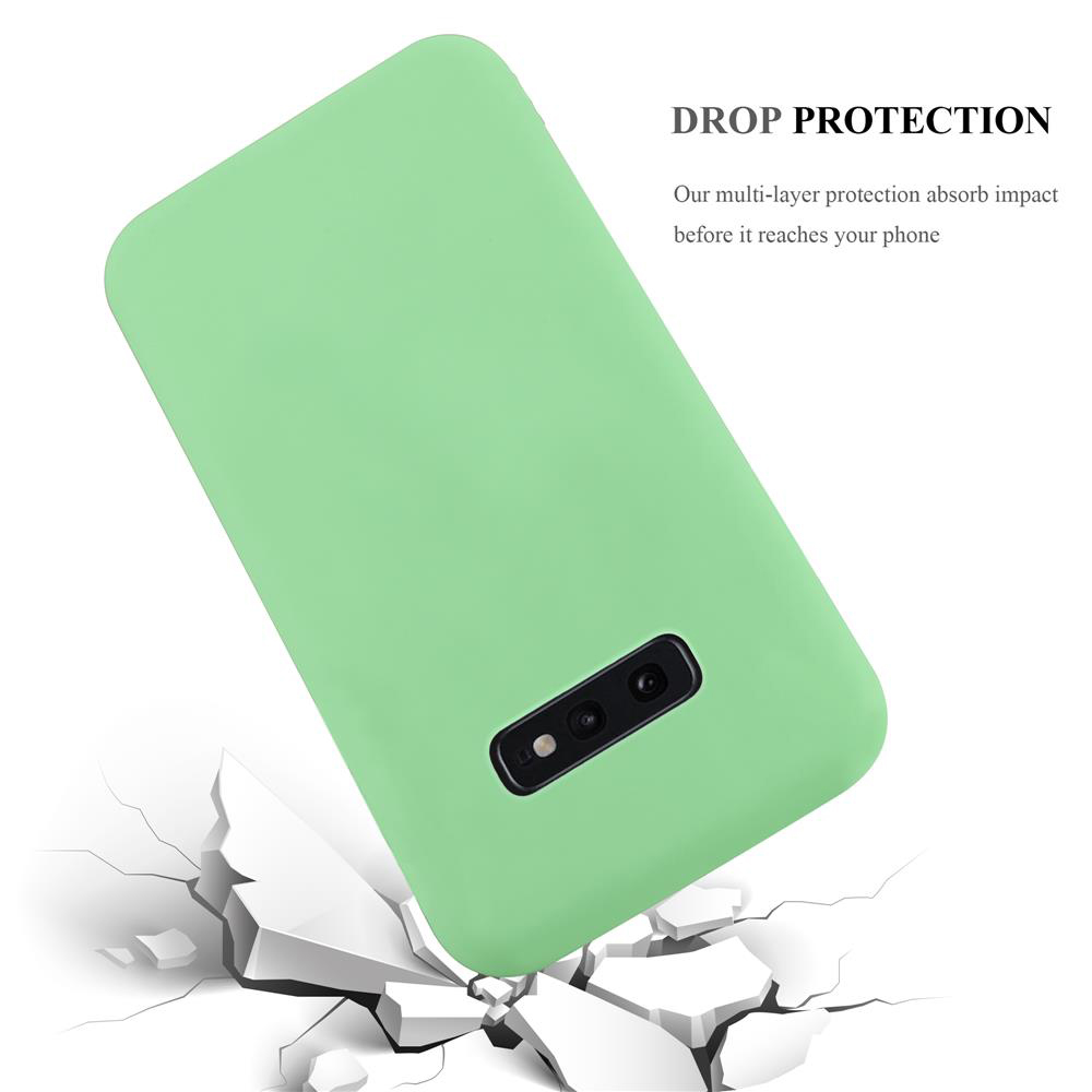 Custodia verde per telefono con ritaglio fotocamera che cade su terreno crepato.