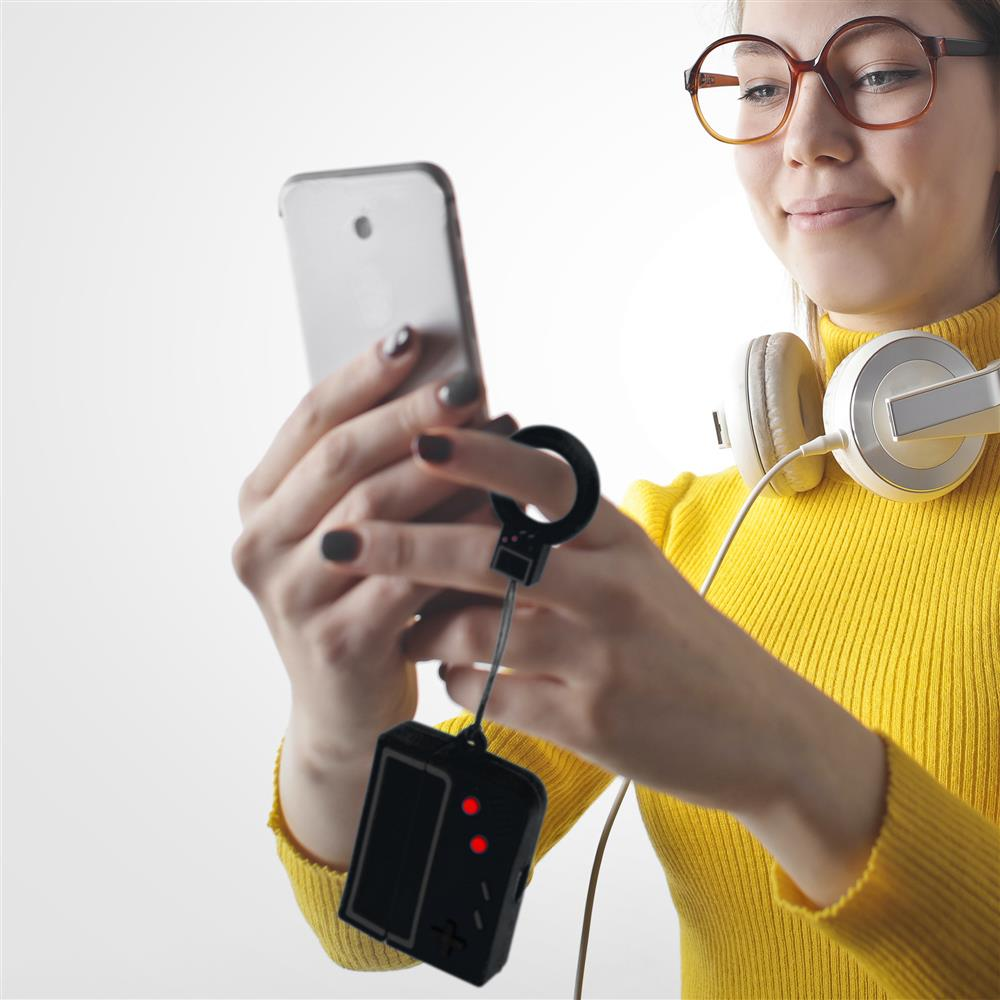 Frau mit Brille und Kopfhörern hält Smartphone mit Gamepad-Anhänger.