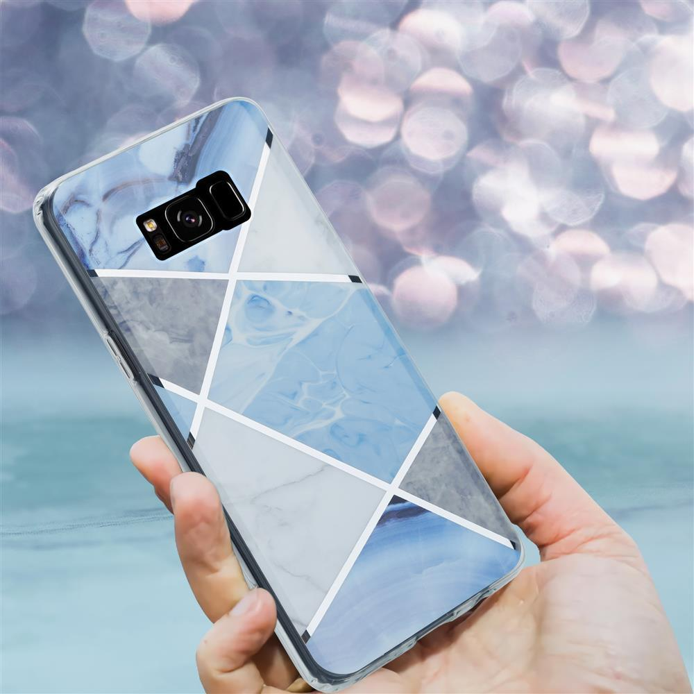 Mano che tiene uno smartphone con cover effetto marmo blu-grigio. Sfondo bokeh.