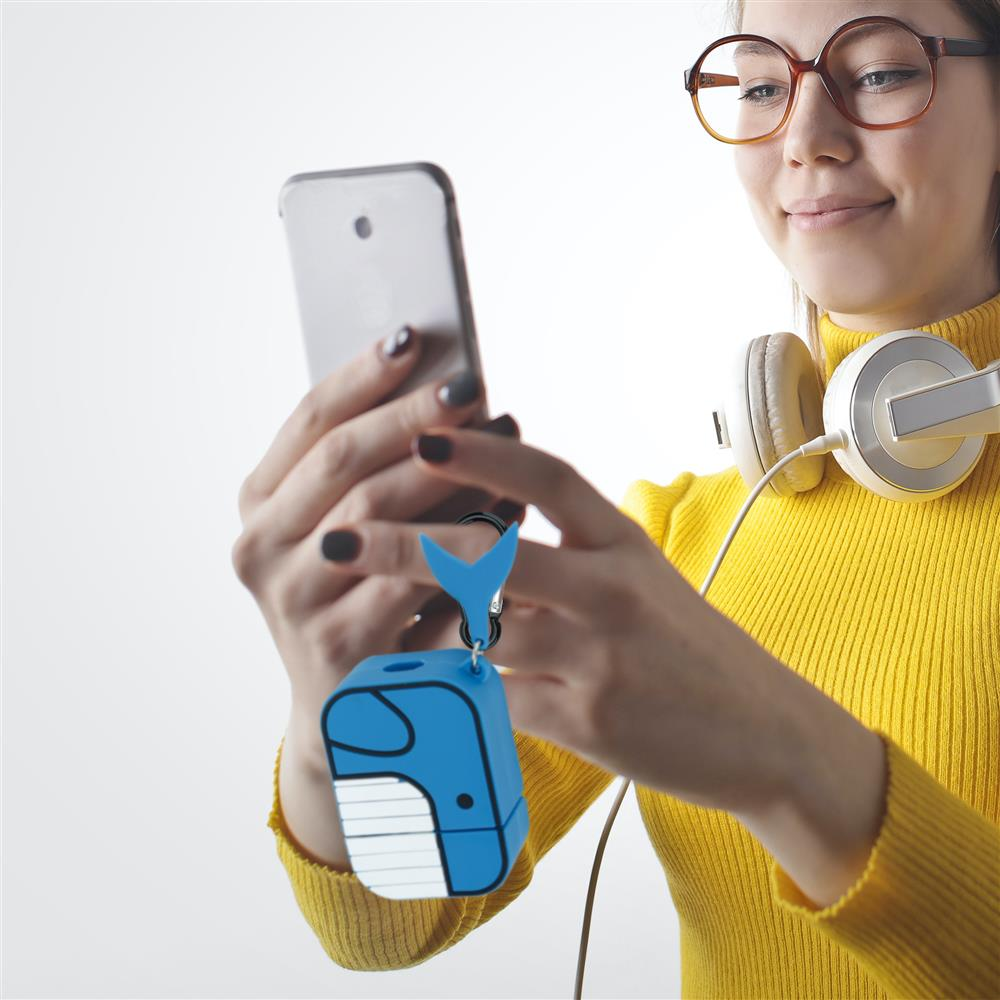 Eine Frau mit Brille und Kopfhörern hält ein Smartphone mit einem blauen Wal-Schlüsselanhänger.