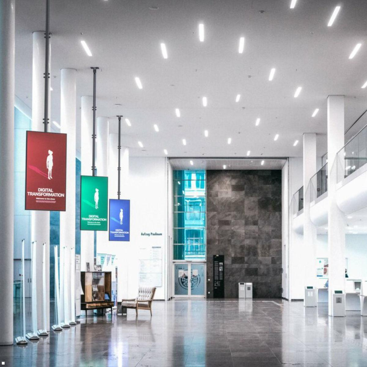 Moderne Lobby mit Hängeanzeigen, Sitzgelegenheiten und Aufzug.
