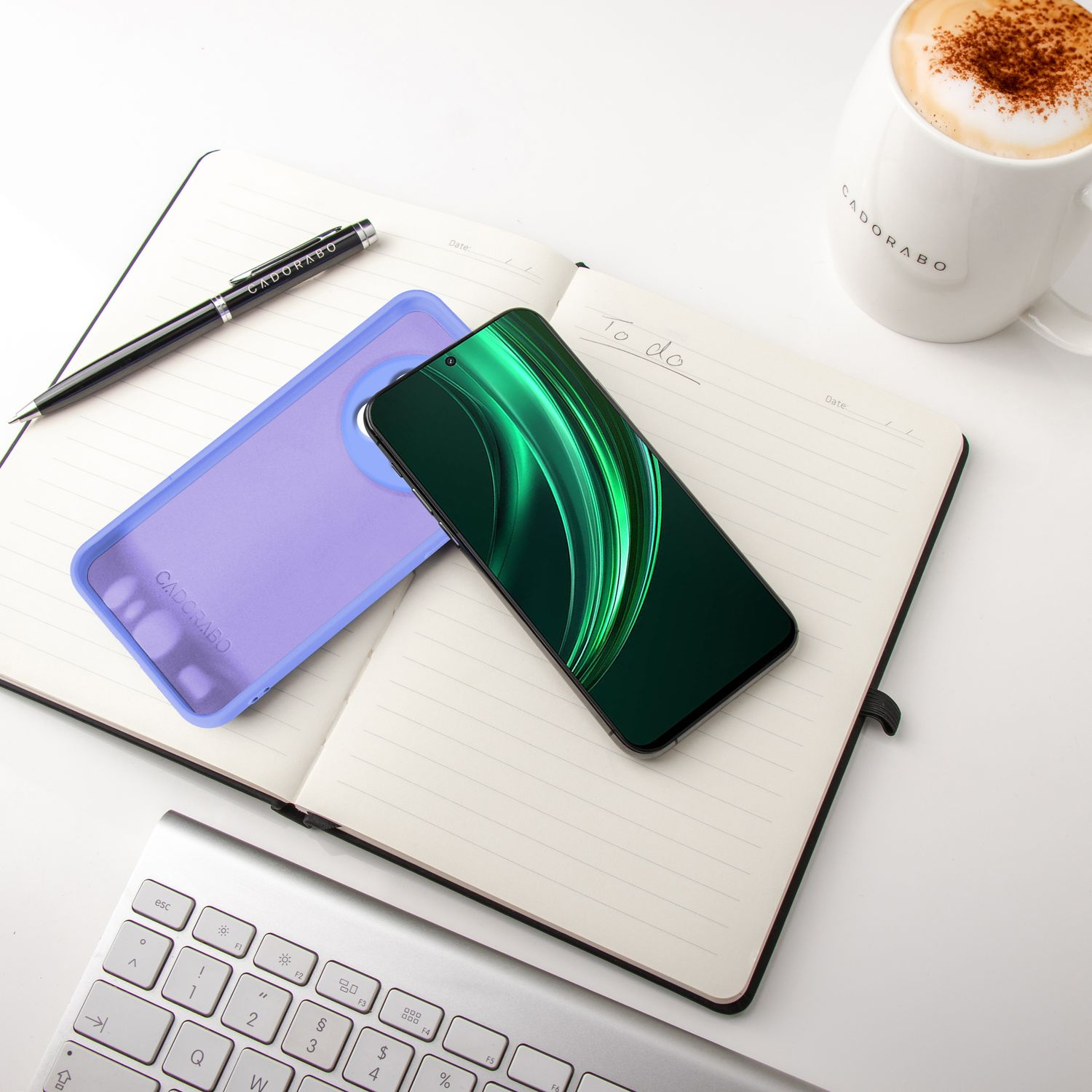 Ein offenes Notizbuch mit einem Smartphone, einer Handyhülle, einem Stift und einer Kaffeetasse.