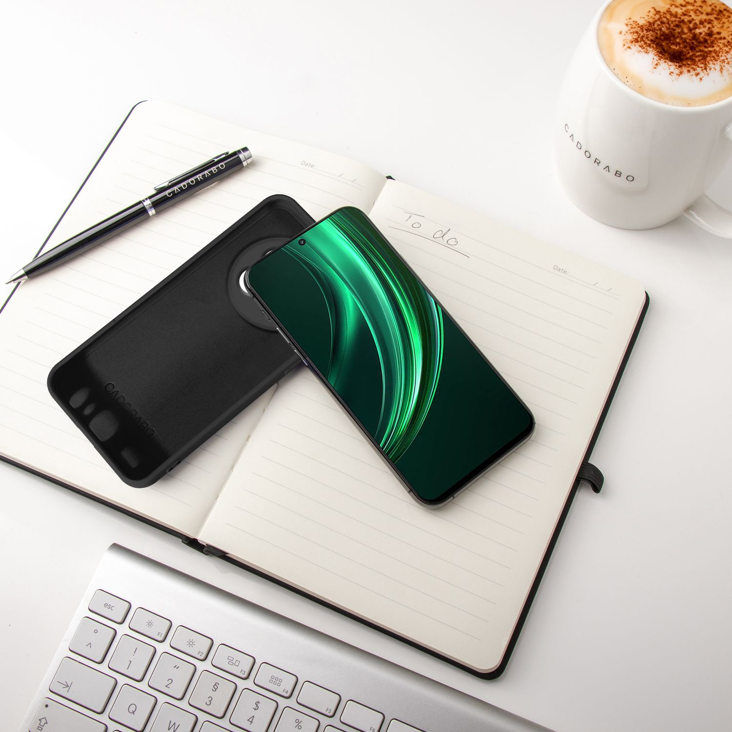 Ein Smartphone liegt auf einem Notizbuch neben einer Kaffeetasse.