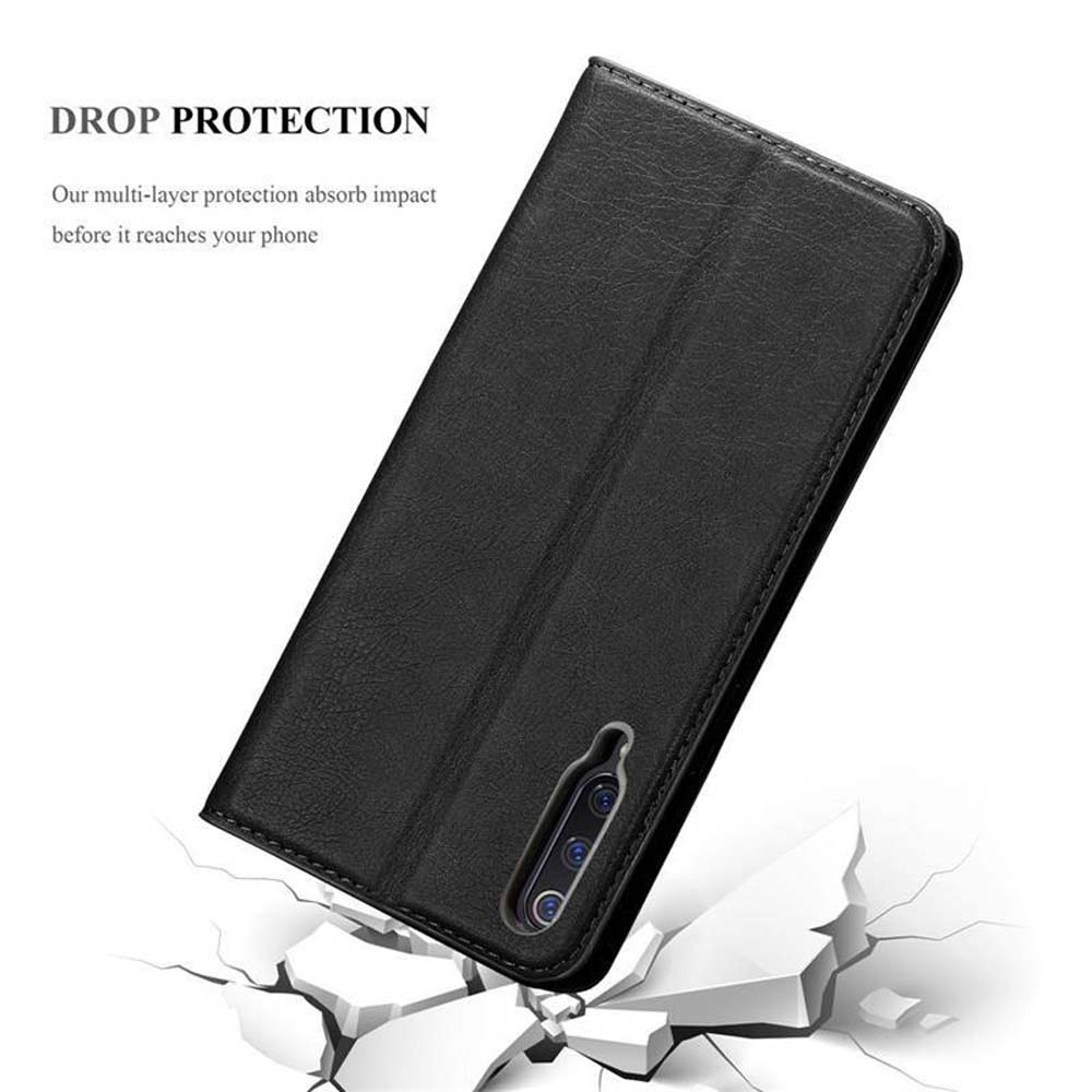 Custodia nera per telefono con tripla lente su terreno incrinato.