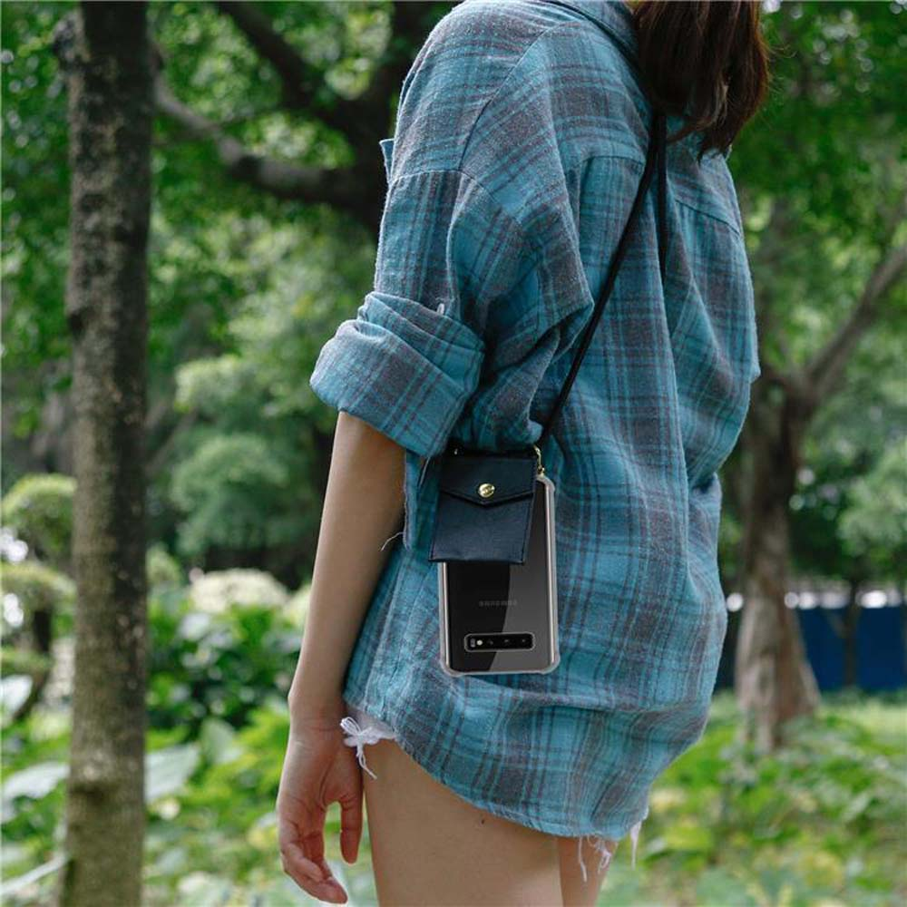 Una donna con camicia a quadri blu indossa una custodia per telefono a tracolla nel parco.