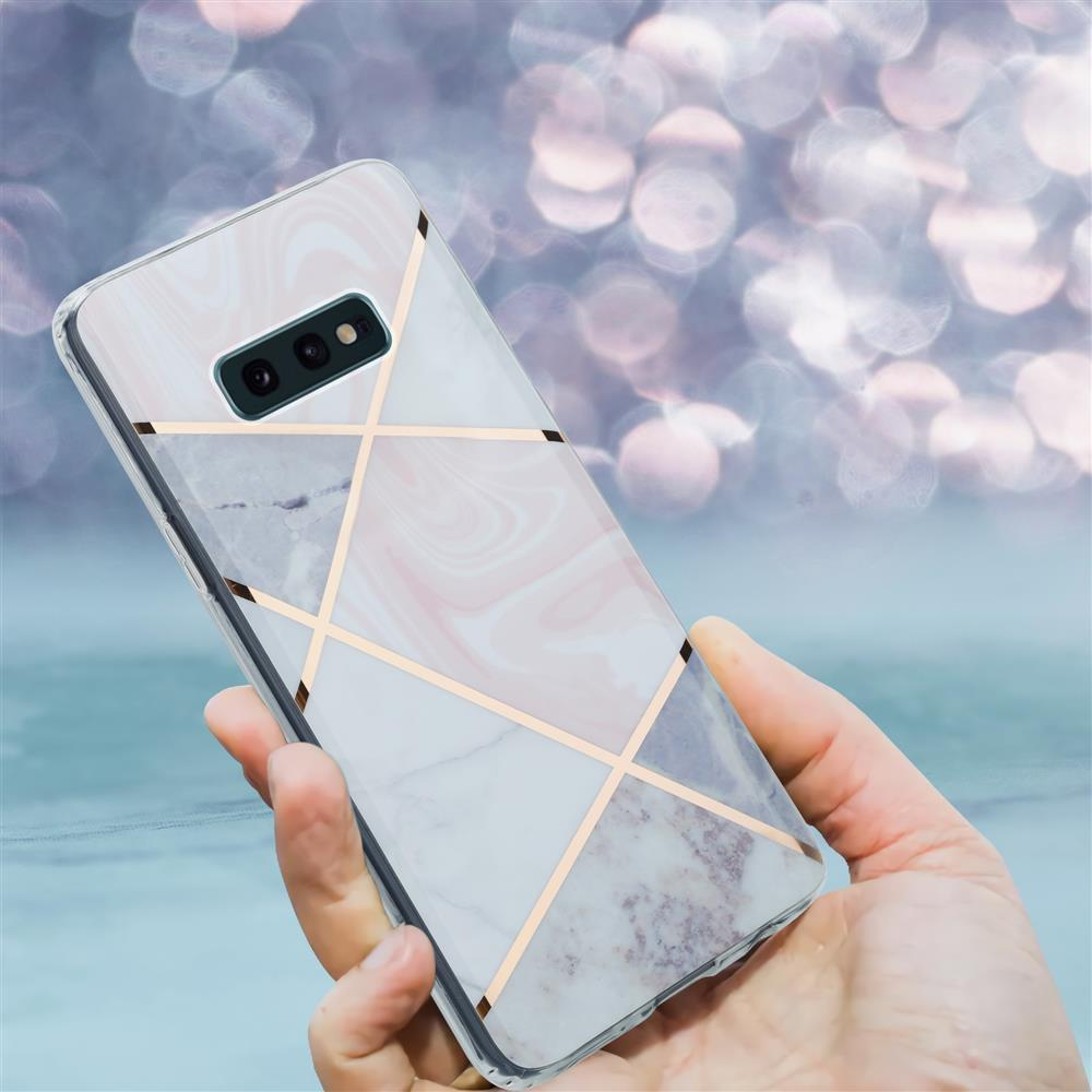 Una mano tiene una cover per telefono con design geometrico in marmo e oro rosa.