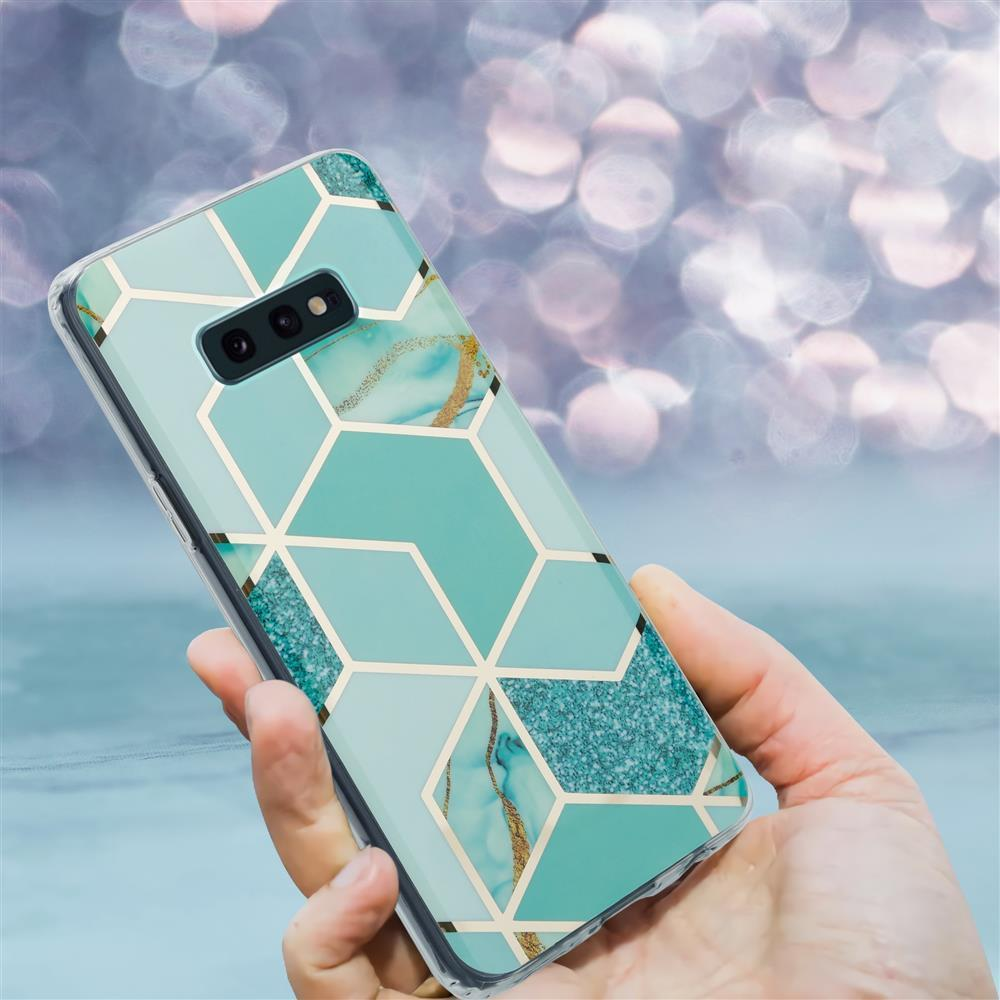 Una mano tiene un telefono con cover turchese e motivo geometrico dorato.