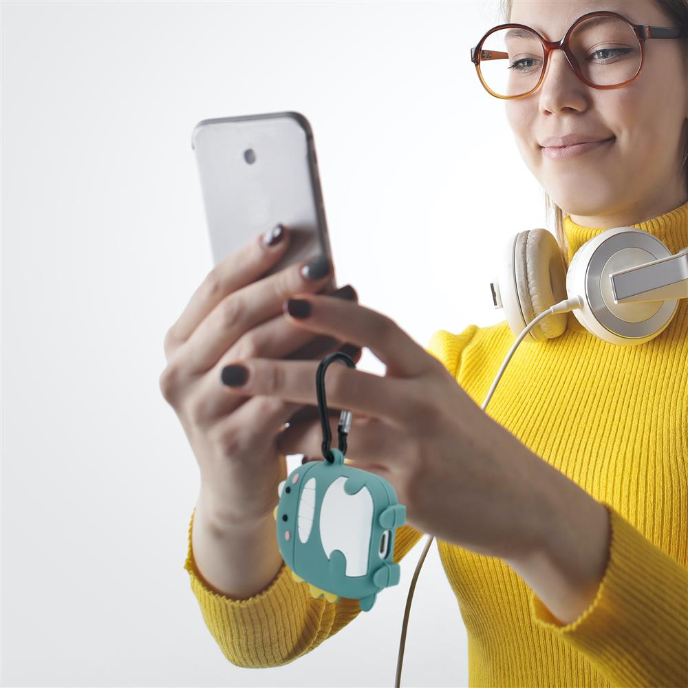 Eine Frau mit Brille und Kopfhörern schaut auf ihr Handy, das sie in der Hand hält.