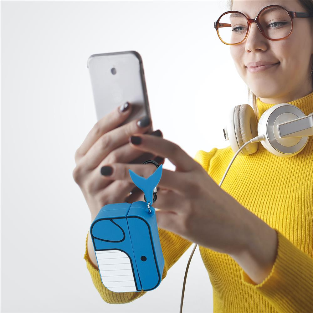 Eine Frau mit Kopfhörern hält ein Handy und einen blauen Wal-Schutzhülle-Schlüsselanhänger.
