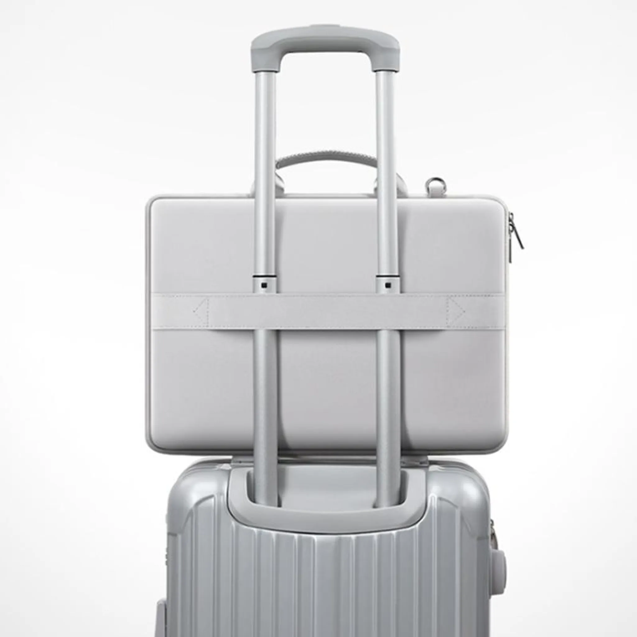 Grauer Koffer mit ausziehbarem Griff und darauf befestigter grauer Laptoptasche.
