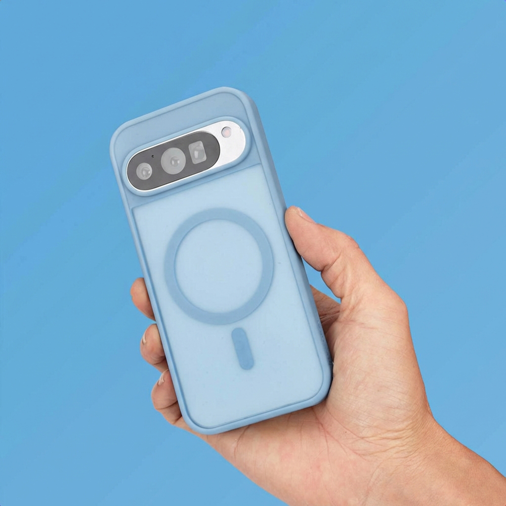 Une main tient une coque de téléphone bleu clair avec des caméras et un anneau magnétique.