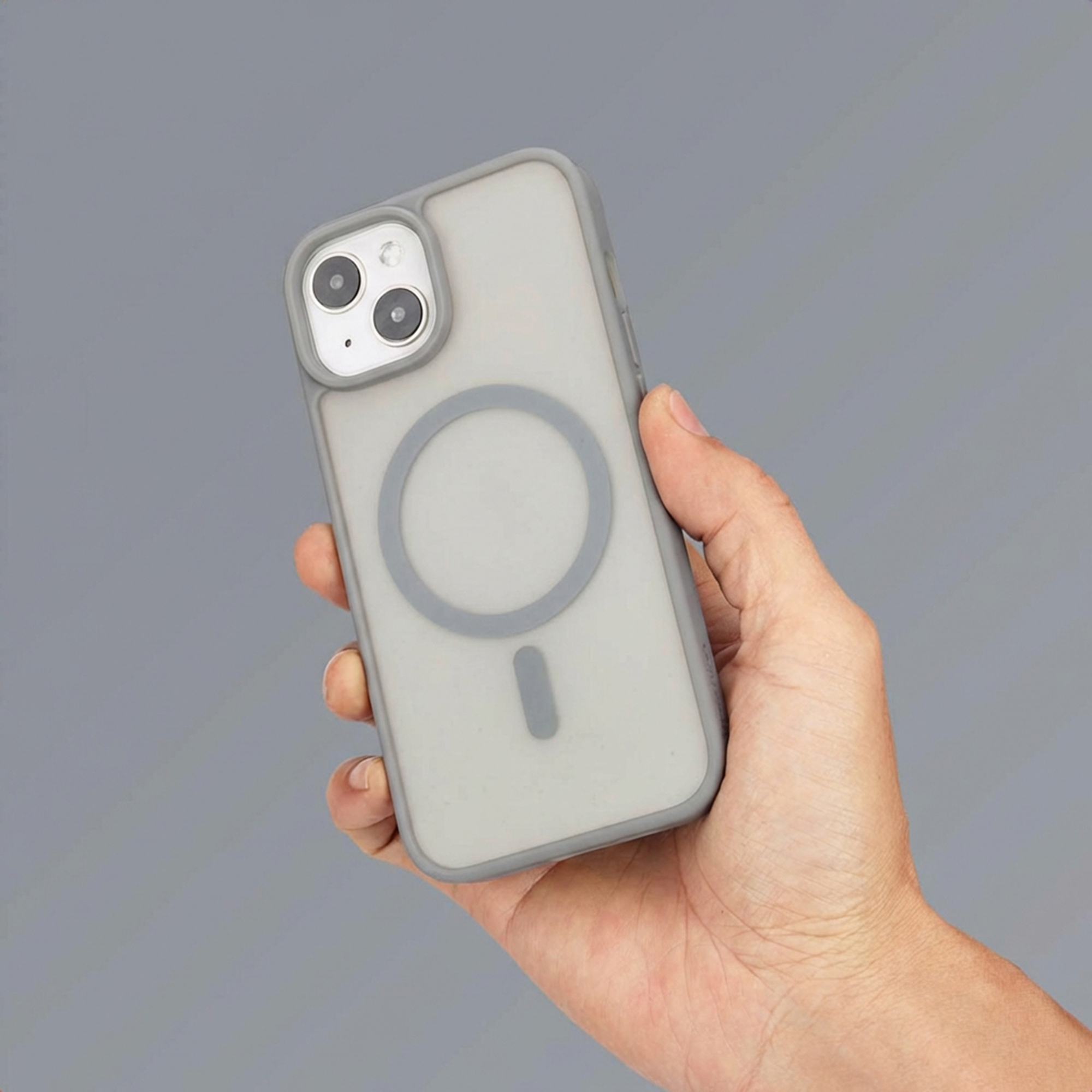 Een hand houdt een grijze iPhone vast met MagSafe-hoes en dubbele camera.